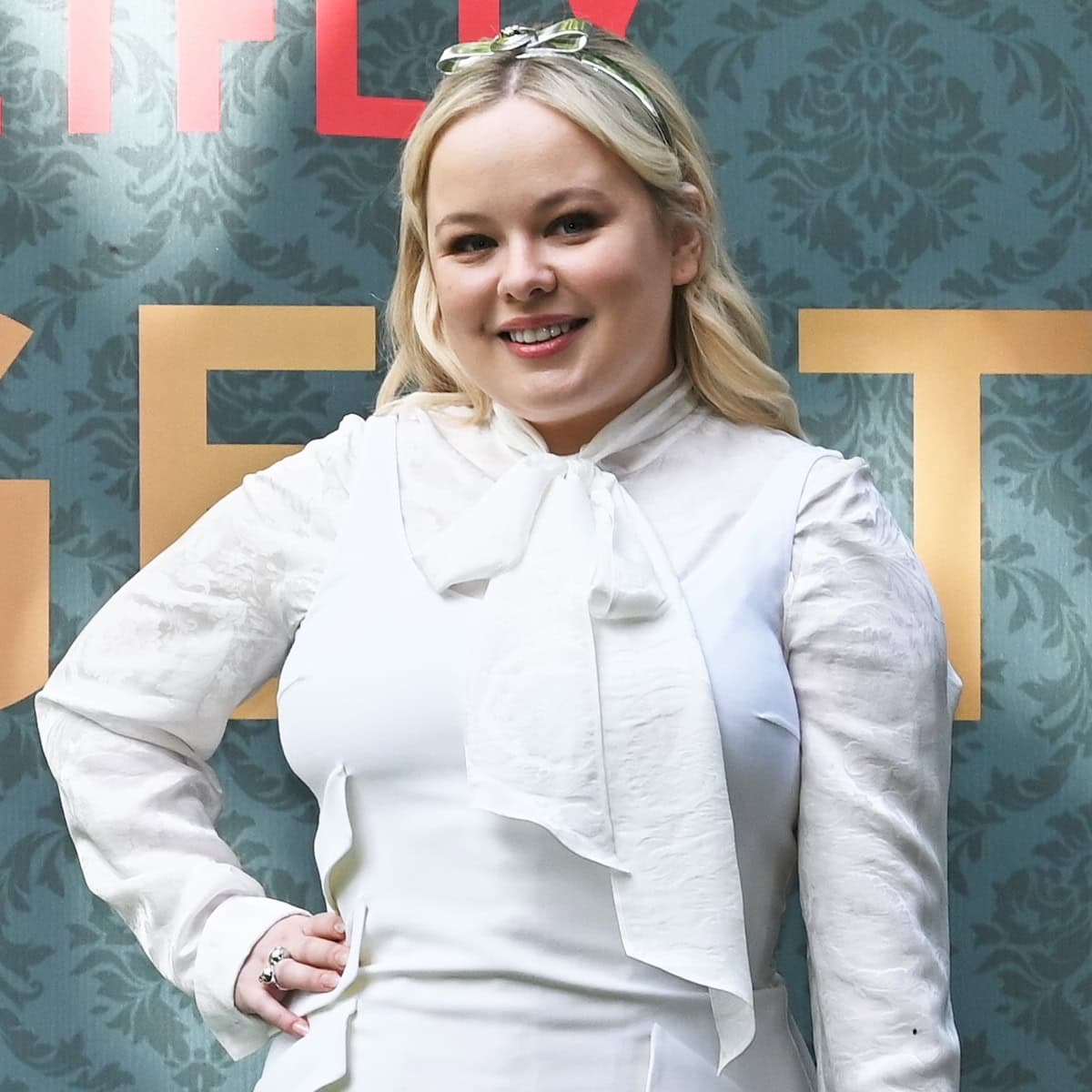Accented by a chic Versace headband and understated jewelry, Nicola Coughlan's accessory choices bring a playful yet refined edge to her outfit