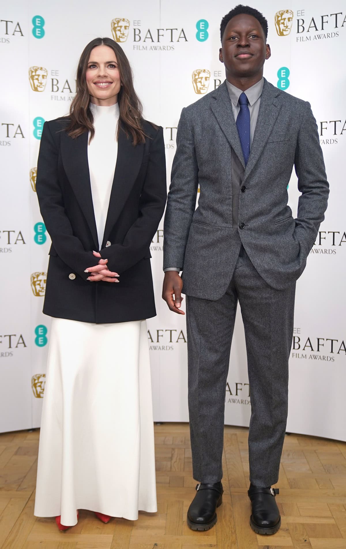 At the 2023 EE BAFTA Film Awards nominations in London, Ted Lasso star Toheeb Jimoh towers over actress Hayley Atwell, who stands at 5 feet 6 inches (167.6 cm) and adds a subtle pop of color with red heels peeking out from beneath her minimalist black-and-white ensemble