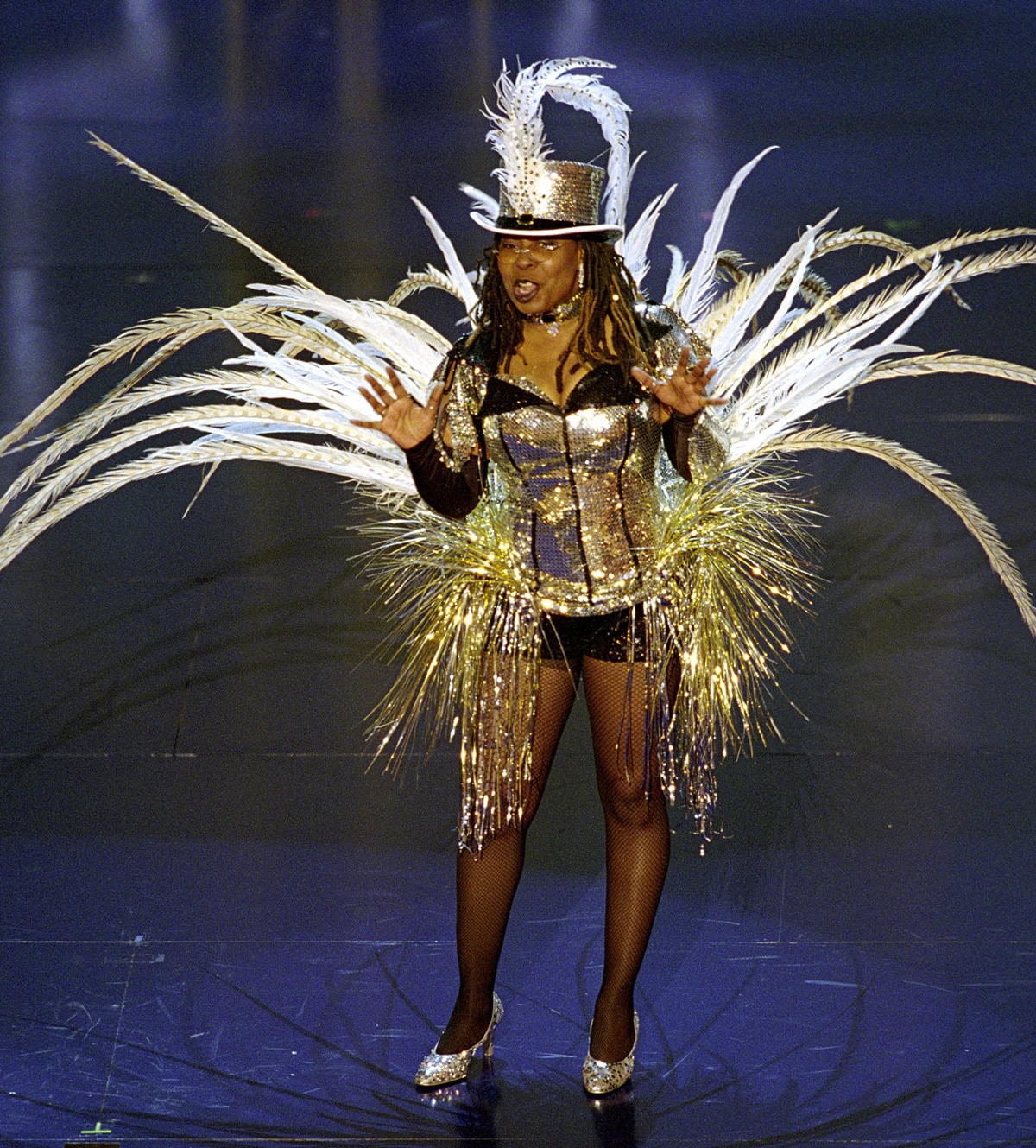 Whoopi Goldberg makes a sparkling statement at the 74th Academy Awards in a feather-trimmed Moulin Rouge–inspired showgirl costume and glittering silver high heels on March 24, 2002
