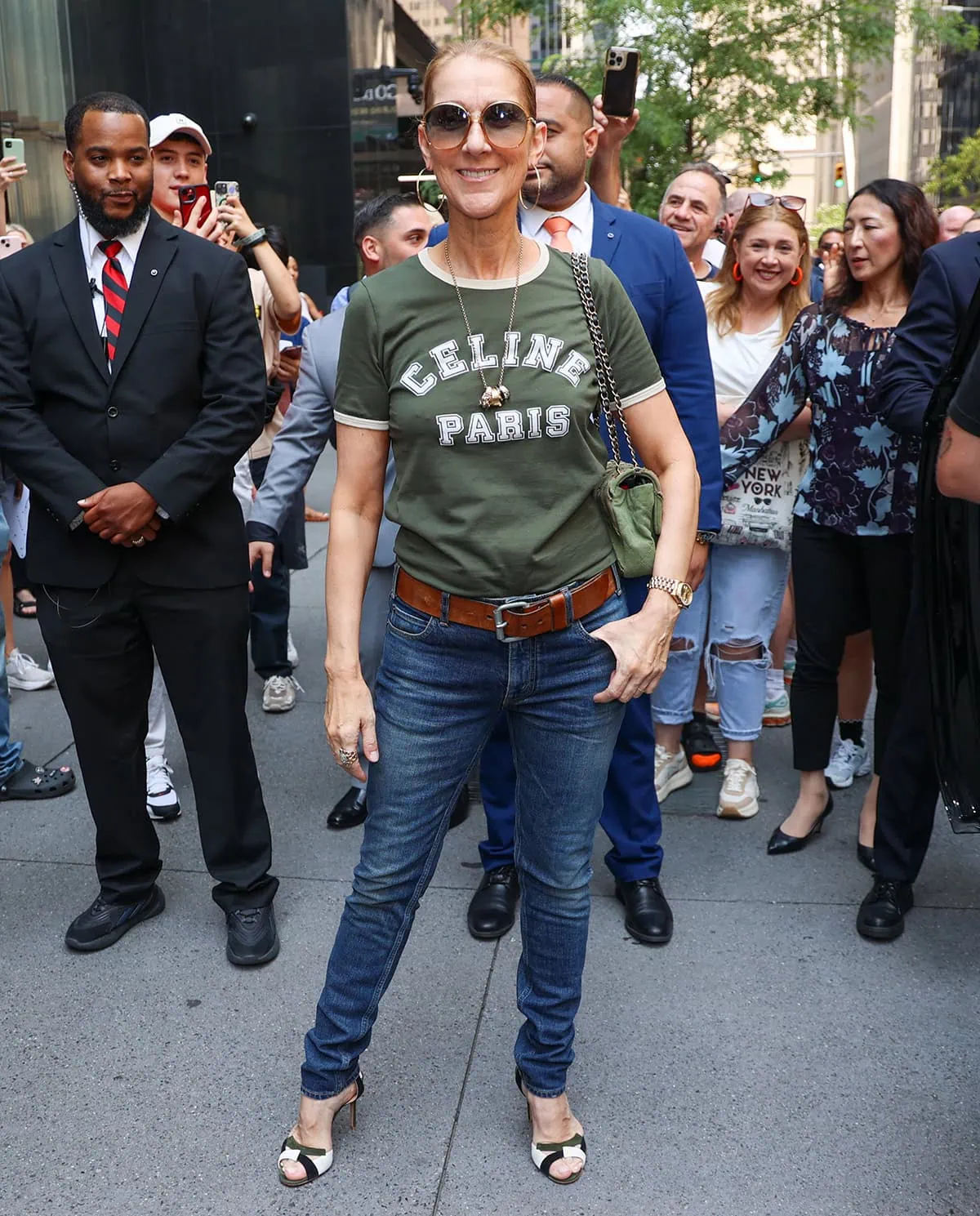 Celine Dion steps out in New York City in a retro-style casual ensemble composed of a green Celine '70s-style logo tee and belted skinny jeans