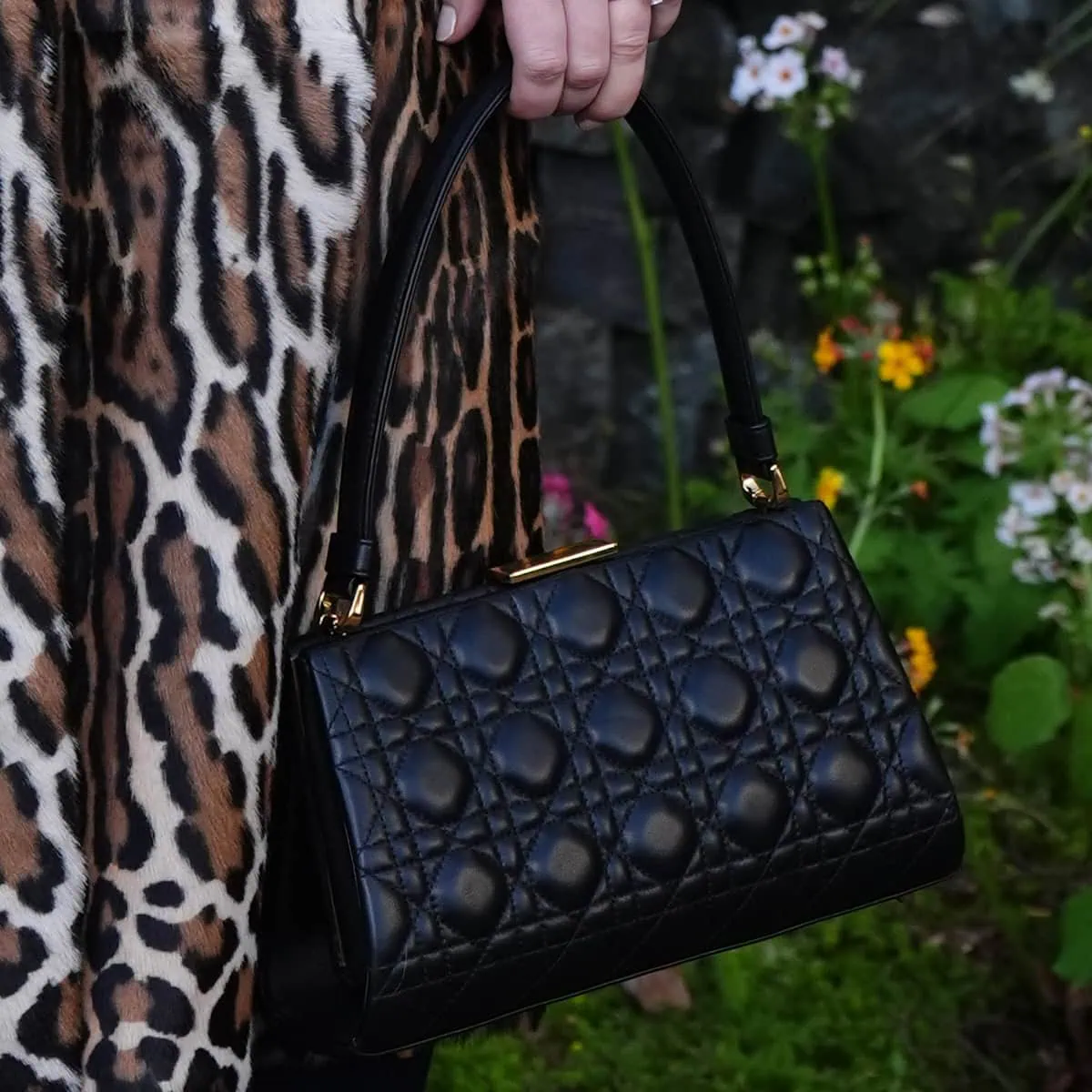 Jennifer Lawrence pairs a classic black quilted Lady Dior top-handle bag with gold hardware, enhancing her chic ensemble at Dior's Cruise 2025 show
