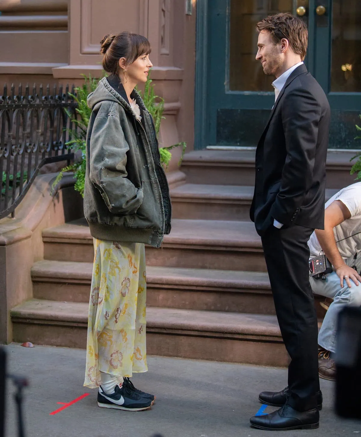 Dakota Johnson pairs a romantic yellow floral dress with white socks and black Nike Daybreak sneakers while filming Materialists opposite Chris Evans in New York City’s West Village