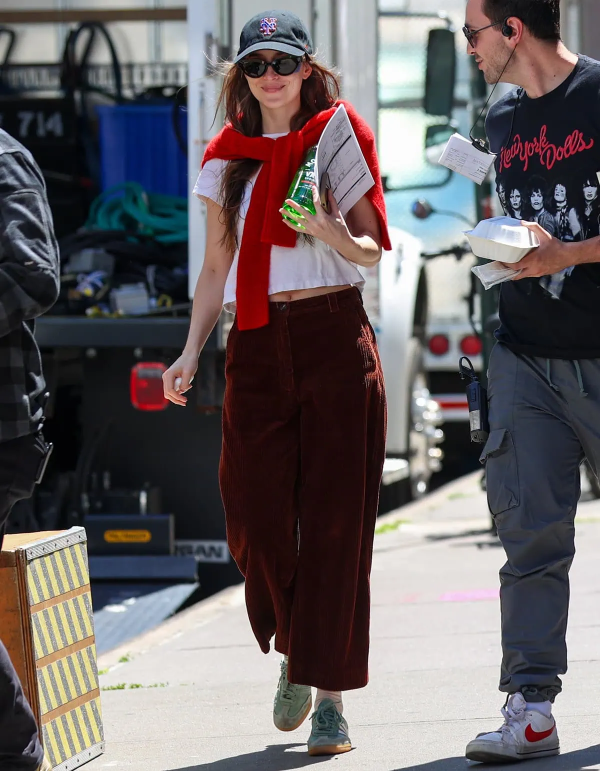 Dakota Johnson keeps it casually polished in a cropped white Re/Done tee, burgundy wide-leg corduroy trousers, and green Adidas Samba sneakers while filming Materialists in New York City
