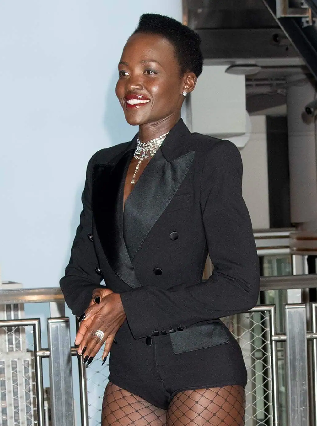 Lupita Nyong'o accessorizes with De Beers jewelry, parts her pixie to the side, and wears bold brown-nude lip gloss
