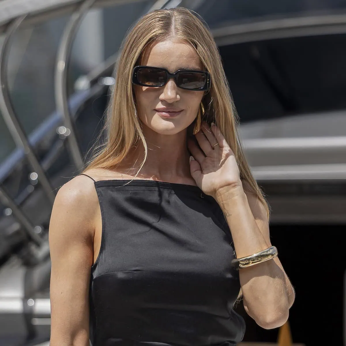Rosie Huntington-Whiteley exudes understated elegance with her Tiffany Co. gold bangle and subtly hidden statement earrings, perfectly complementing her chic black ensemble at the Jacquemus 2024 Cruise fashion show