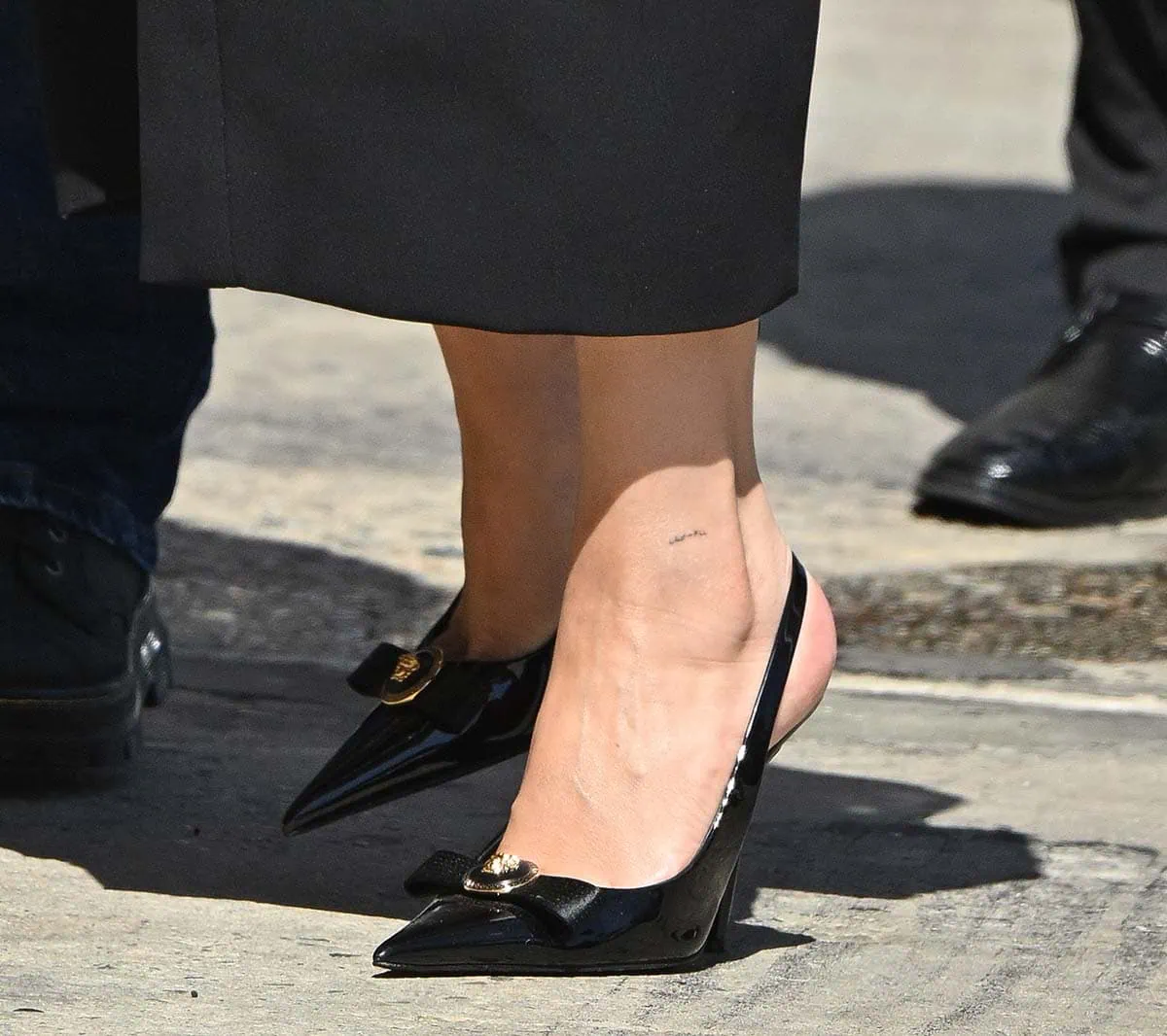 Selena Gomez completes her Versace ensemble with the glossy black “Gianni” slingback pumps, detailed with chic bows and signature Medusa hardware that add a feminine yet powerful finish to her look