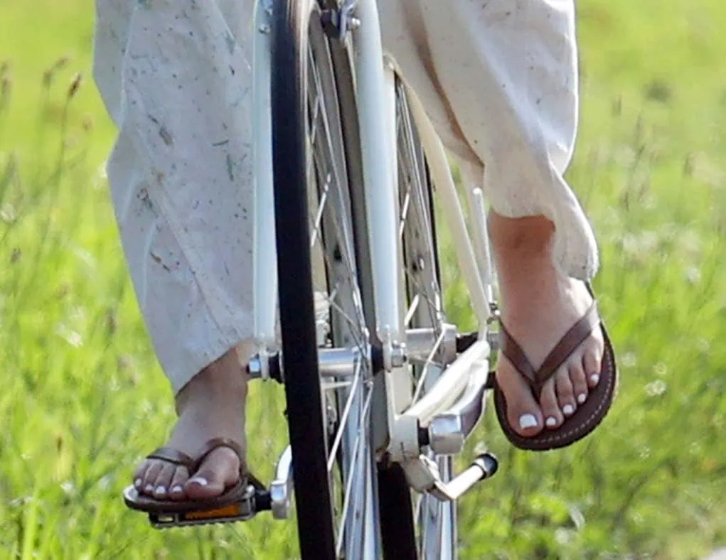 Jennifer Lopez pedals through the Hamptons in brown leather flip-flops, showing off her relaxed summer style as she bikes in paint-splattered Ralph Lauren overalls