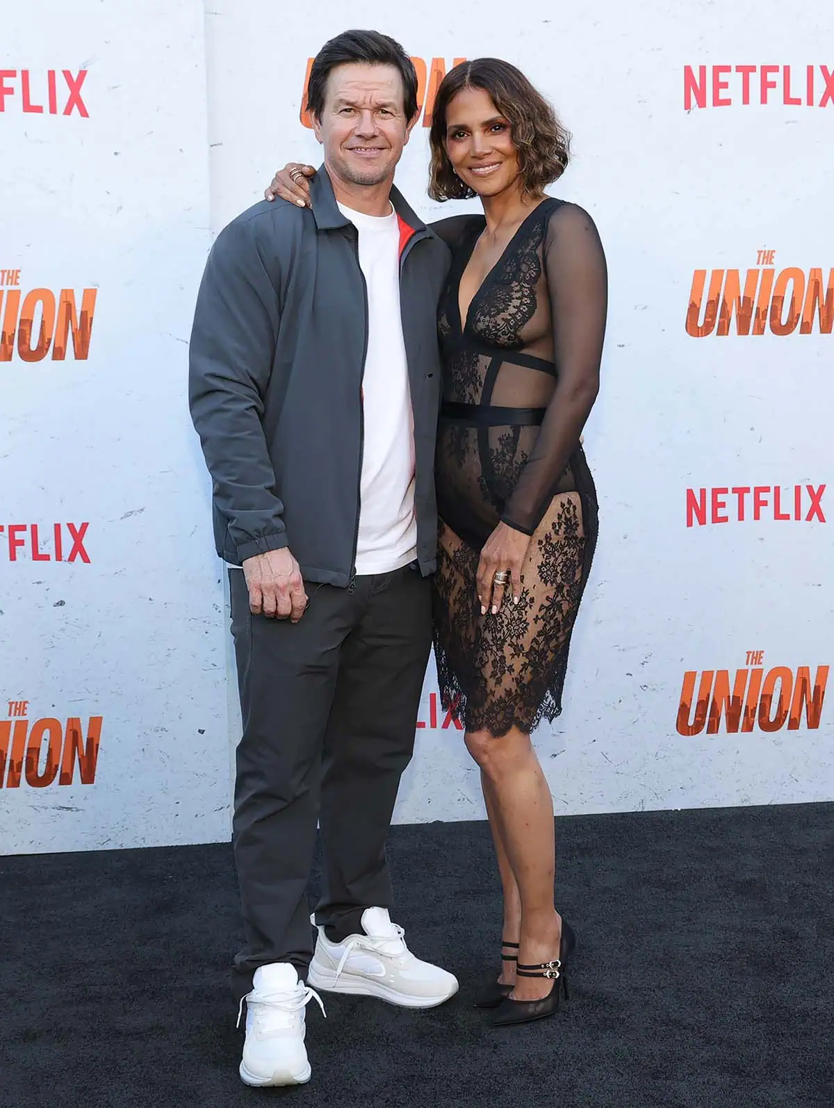 Halle Berry pairs her sheer black La Perla lace dress with elegant Dolce Gabbana mesh Mary Jane pumps as she poses with Mark Wahlberg at The Union premiere