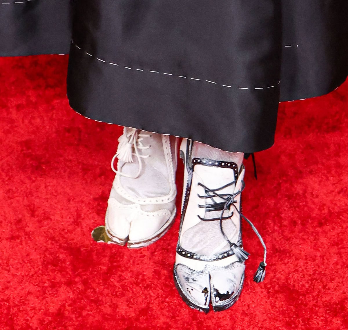 Doechii embraces her quirkiness in Maison Margiela's black-and-white Tabi Bourgeoise Spectator pumps featuring perforated pinked trims, lace-up ties with tassel ends, Margiela's Tabi split toes, and high heels