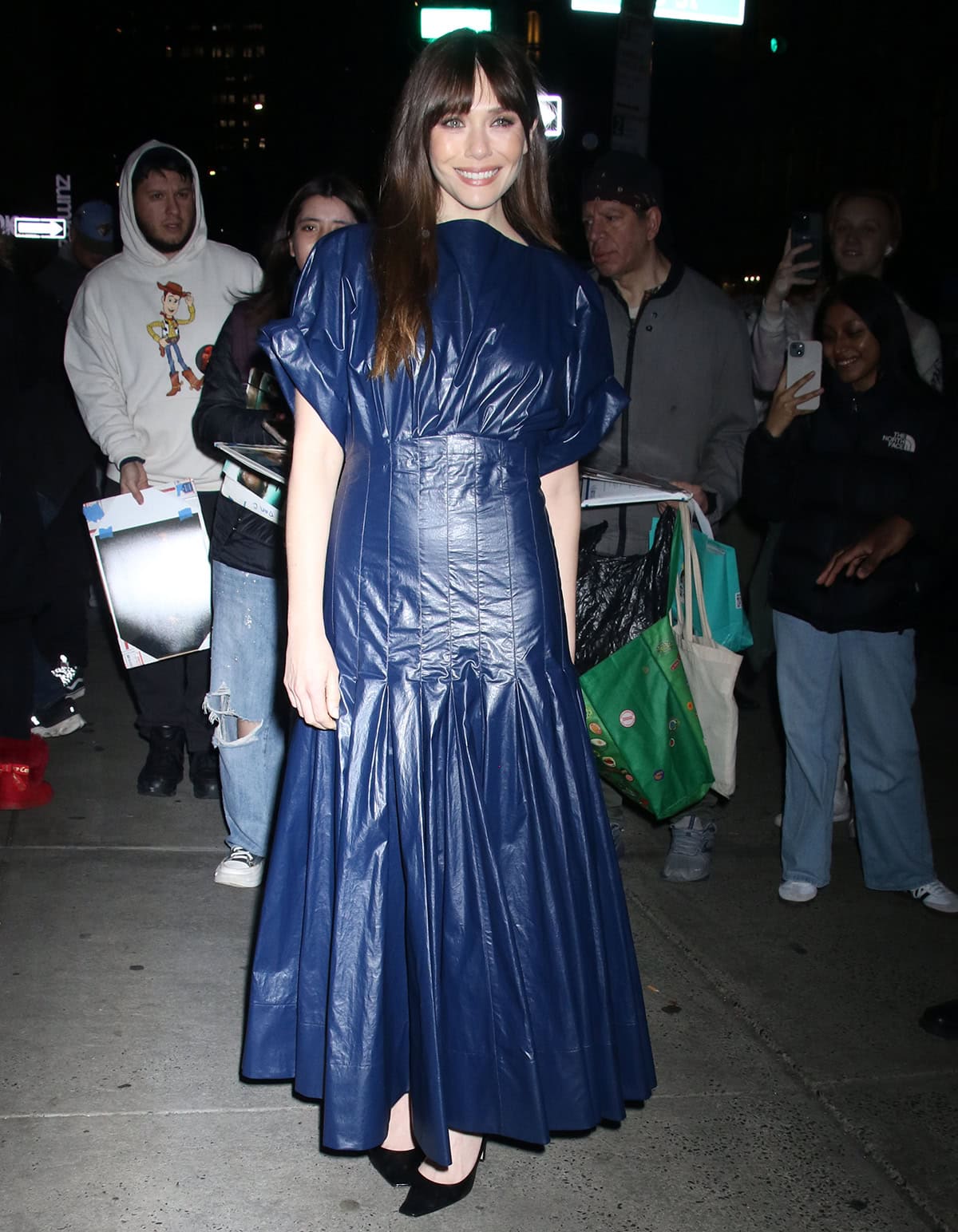 Elizabeth Olsen fails to wow in a navy PVC dress as she attends a QA screening for her latest sci-fi thriller, The Assessment