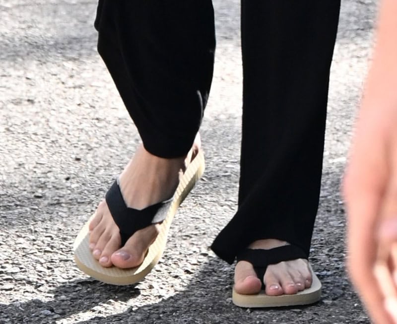 Hailey Bieber teams her Pilates attire with The Row flip-flops featuring thick black grosgrain straps and cream rubber soles