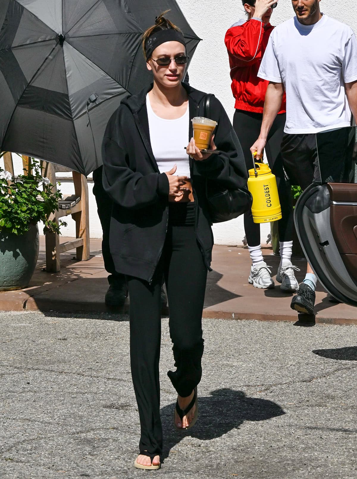 Hailey Bieber embraces minimalism in a chic white cropped bralette, black leggings, and oversized Russell Athletic jacket