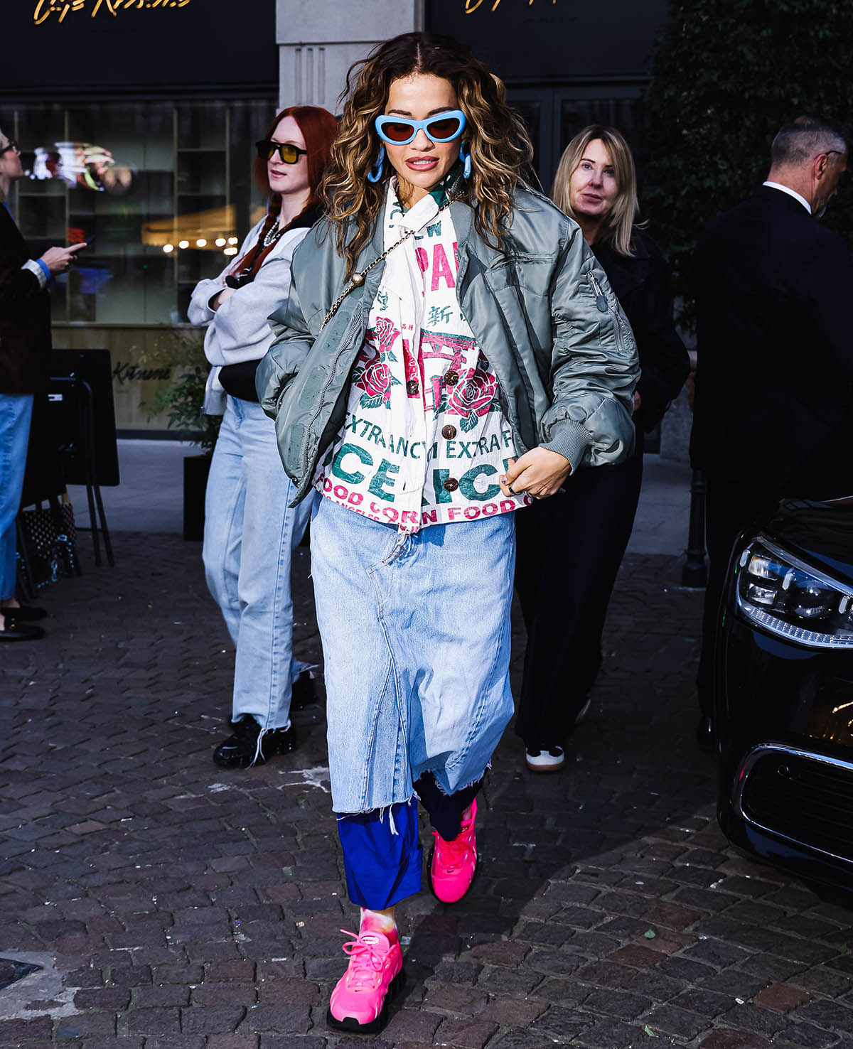 Rita Ora looks chic wearing a graphic vintage rice sack shirt with a khaki satin bomber jacket