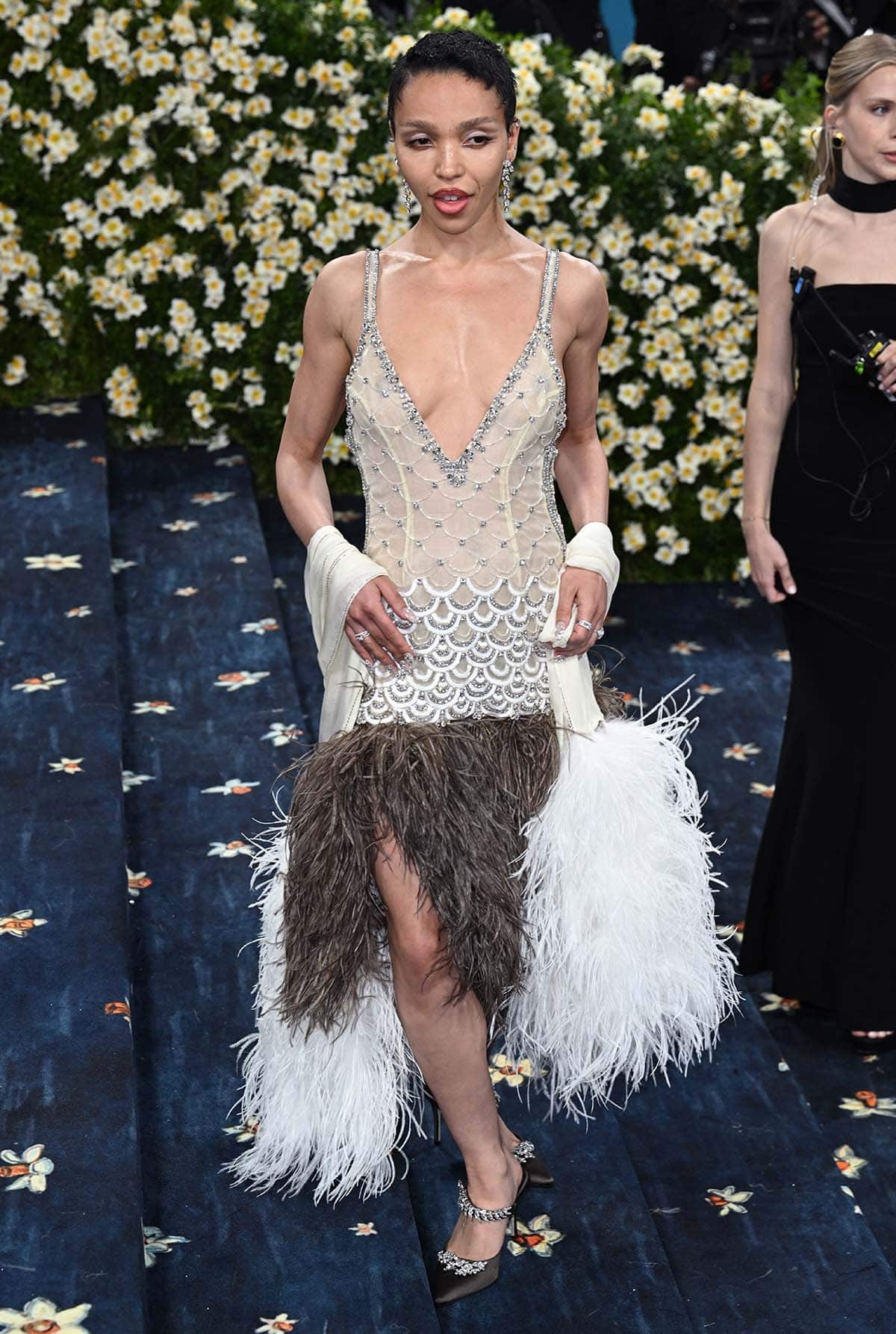 FKA Twigs embraces the 1920s in a Wales Bonner flapper dress featuring a crystal scalloped pattern, a plunging neckline, a drop waist, and an ostrich feather skirt