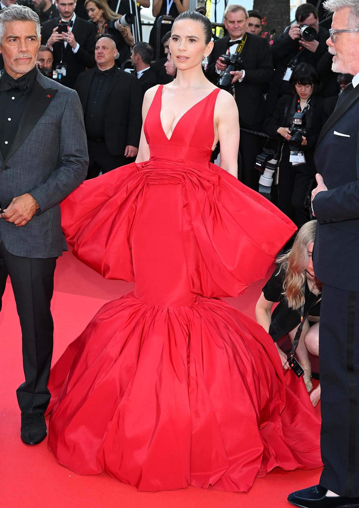 Hayley Atwell is fierce and hot in a red Giambattista Valli gown featuring a plunging neckline, an oversized bow, and a mermaid skirt at the Mission: Impossible – The Final Reckoning Cannes premiere