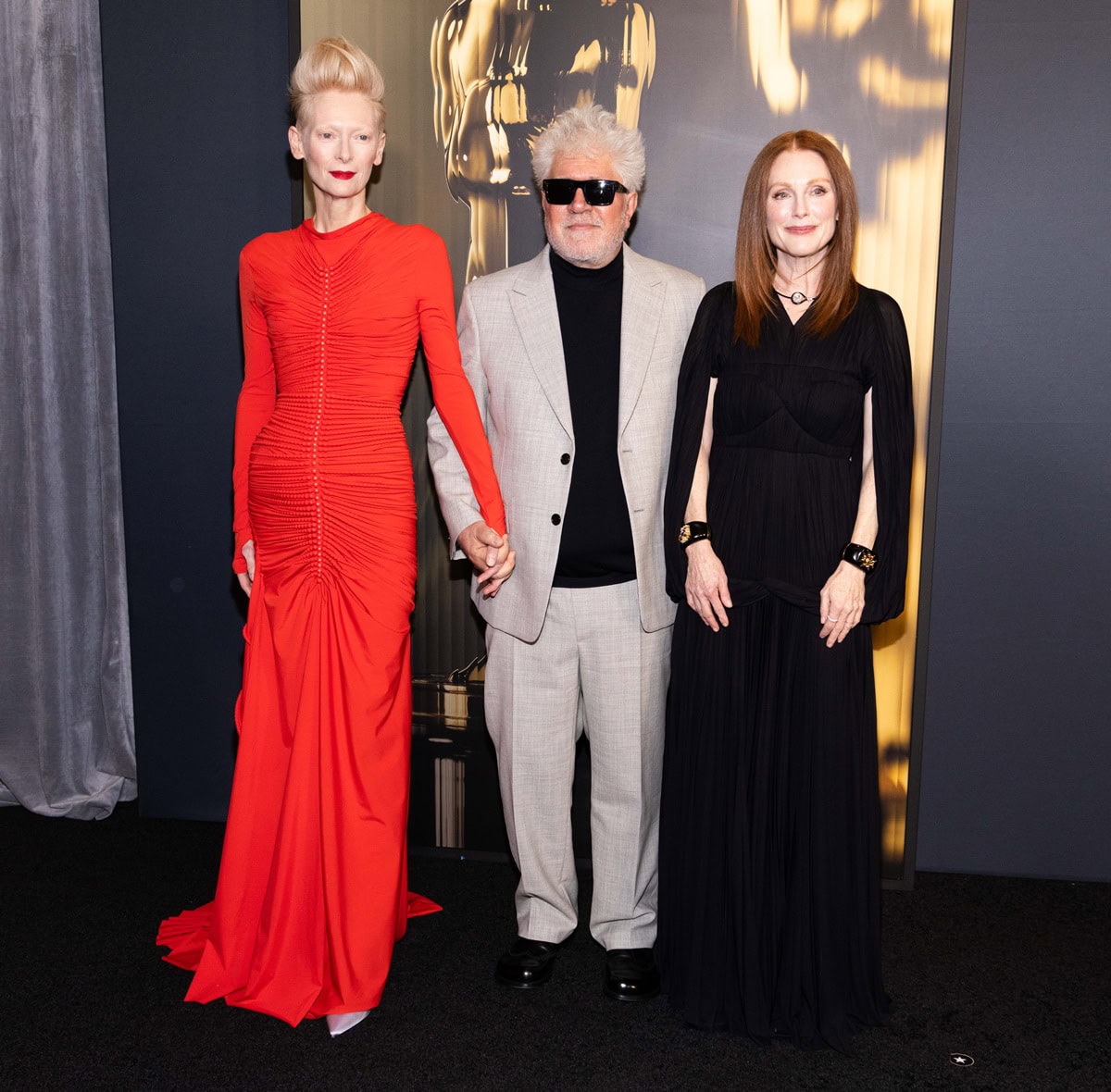 Julianne Moore stuns in a black Proenza Schouler Rumi pleated maxi dress, standing beside the much taller Tilda Swinton and Pedro Almodóvar at the 15th Governors Awards in Hollywood