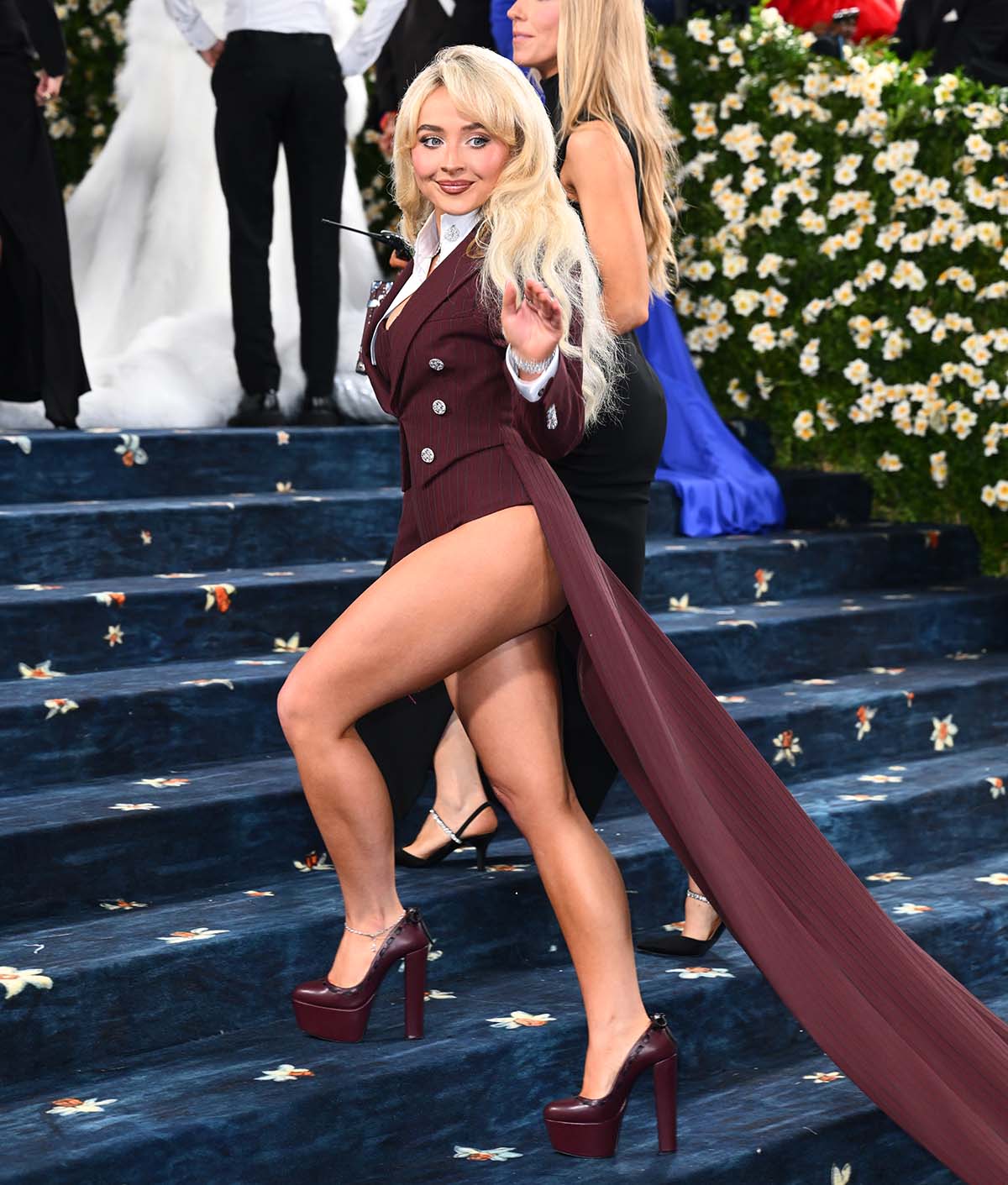 Sabrina Carpenter goes pantless, pairing her burgundy pumps with a matching burgundy pinstripe blazer with a long train