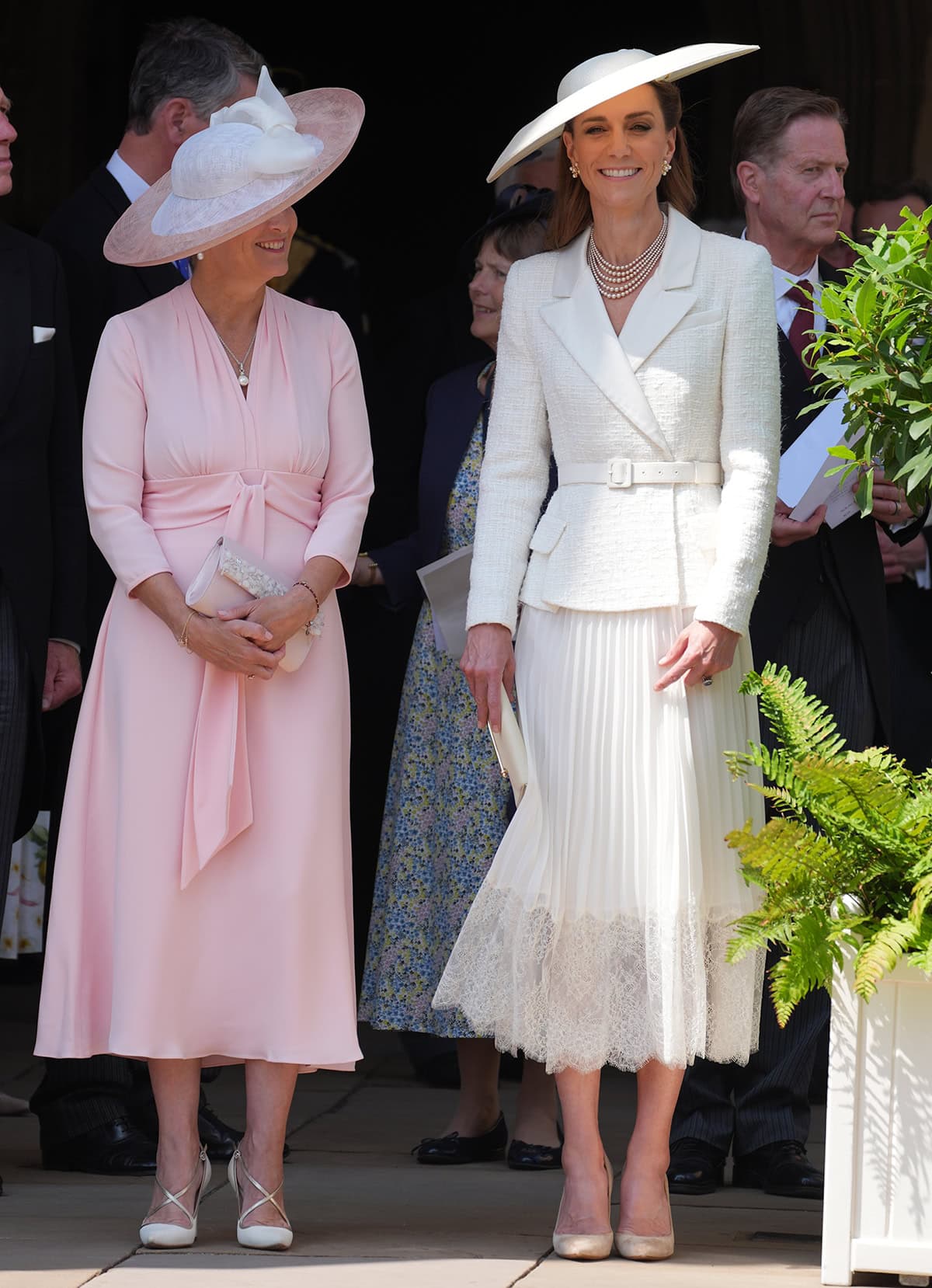 Kate Middleton, pictured with The Duchess of Edinburgh, is the epitome of summer elegance in a white Self-Portrait dress featuring a boucle tweed jacket bodice and a pleated midi skirt with a lace hem