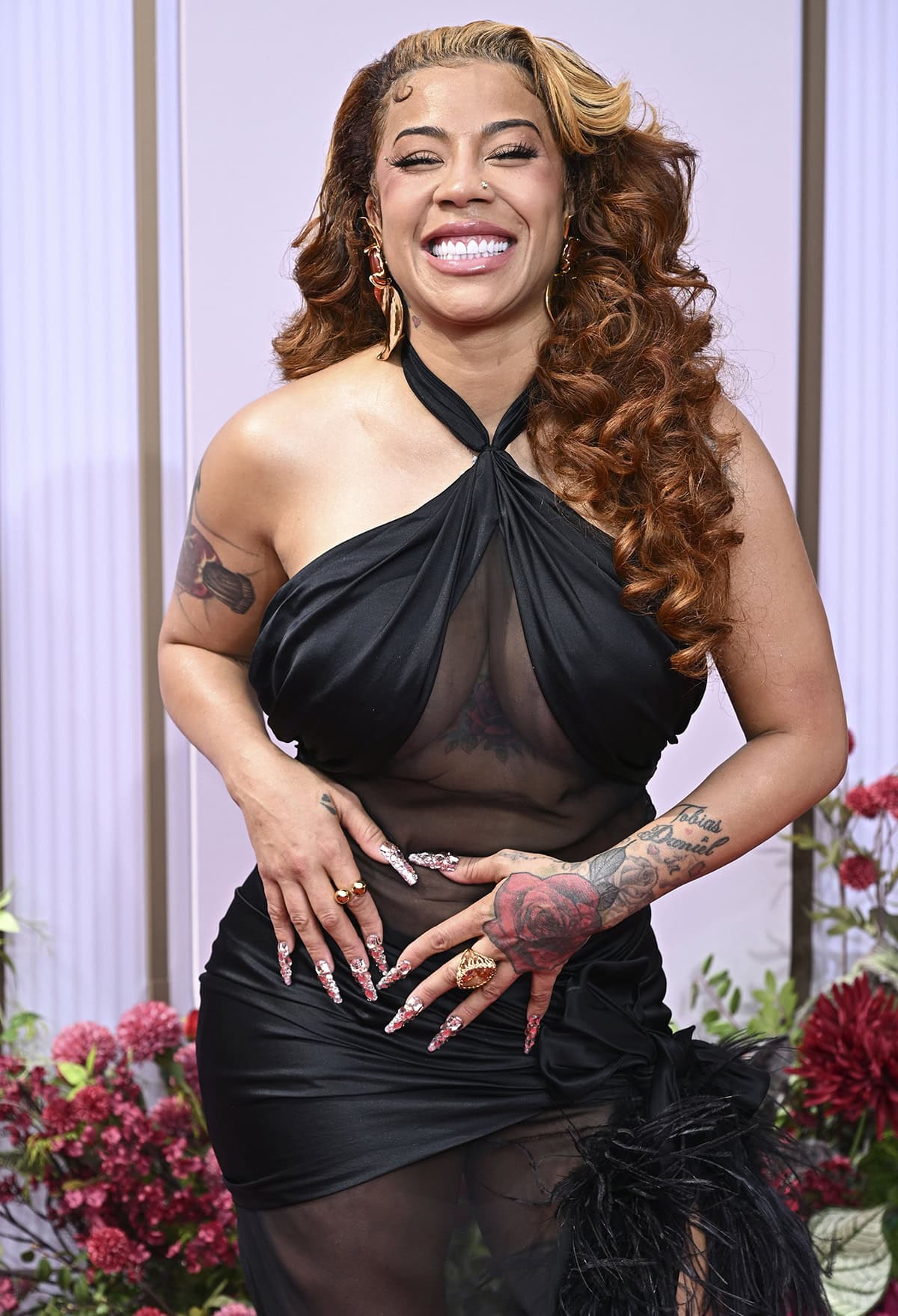 Keyshia Cole stuns in a sheer gown with a ruched halter bodice, a draped waist, and a feather-trimmed sweeping train