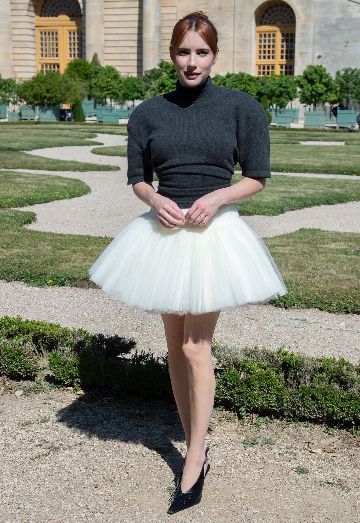 Emma Roberts parades her slim legs in a white tutu tulle skirt and a gray knit short-sleeved sweater with padded shoulders and a turtleneck by Jacquemus