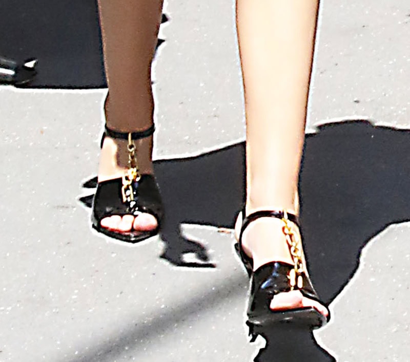 Julia Butters completes her playful yet sophisticated monochromatic ensemble with Balmain Sync sandals featuring a gold-tone chain T-strap, open toes, ankle straps, and high heels