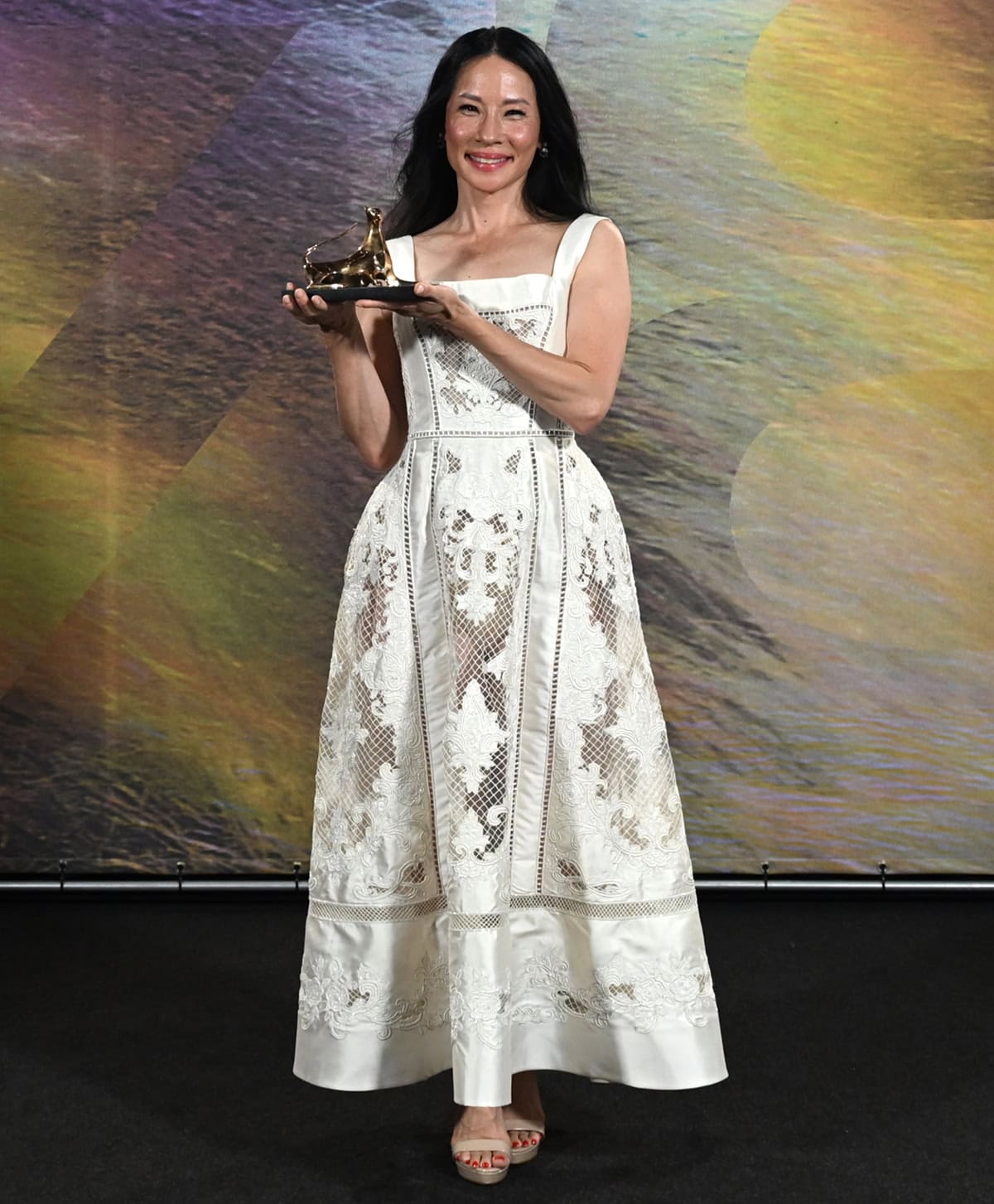Lucy Liu stuns in a white embroidered Paolo Sebastian dress made of white silk mikado with net panels, cutout embroideries, thick shoulder straps, and a sculpted square neck