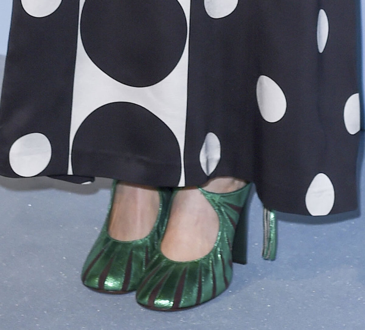 Elizabeth Olsen adds a pop of color to her modern black-and-white dress by wearing a pair of metallic green Dries Van Noten pumps with crisscross lace-up ties, black cutouts, and high heels