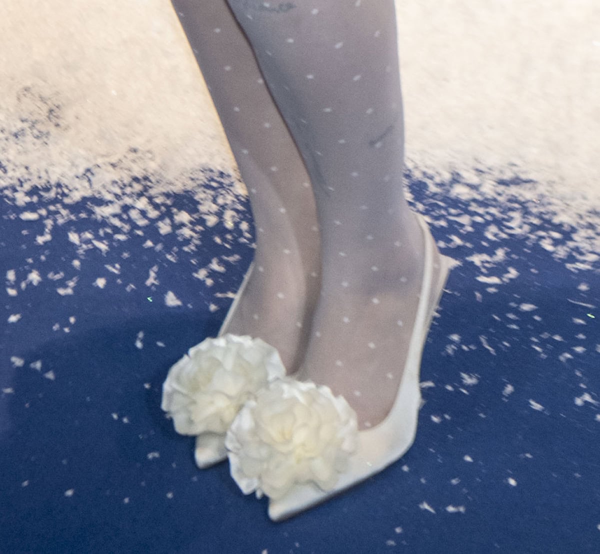 Anne-Marie embraces winter-white glamour in polka-dot stockings and white slingback pumps with an intricate 3D floral accent