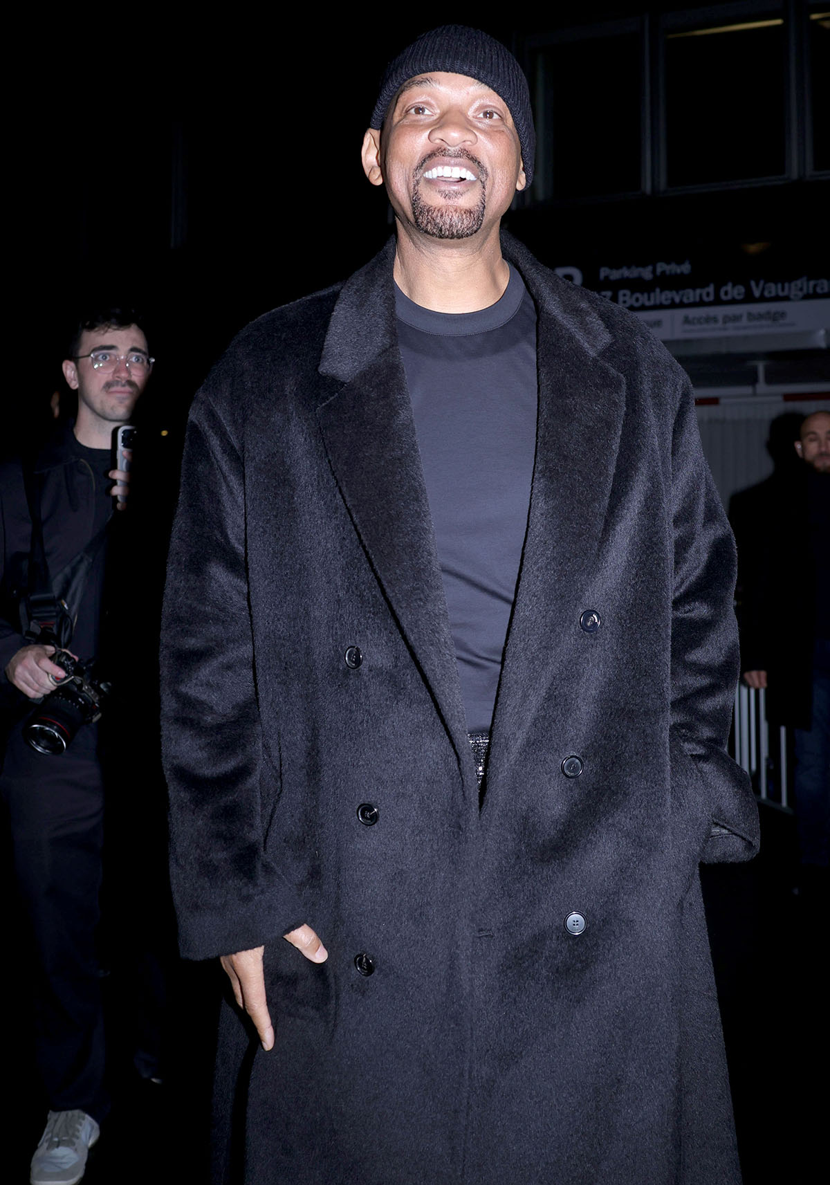 Will Smith pairs his boots with a simple black tee, a black coat, and tweed pants