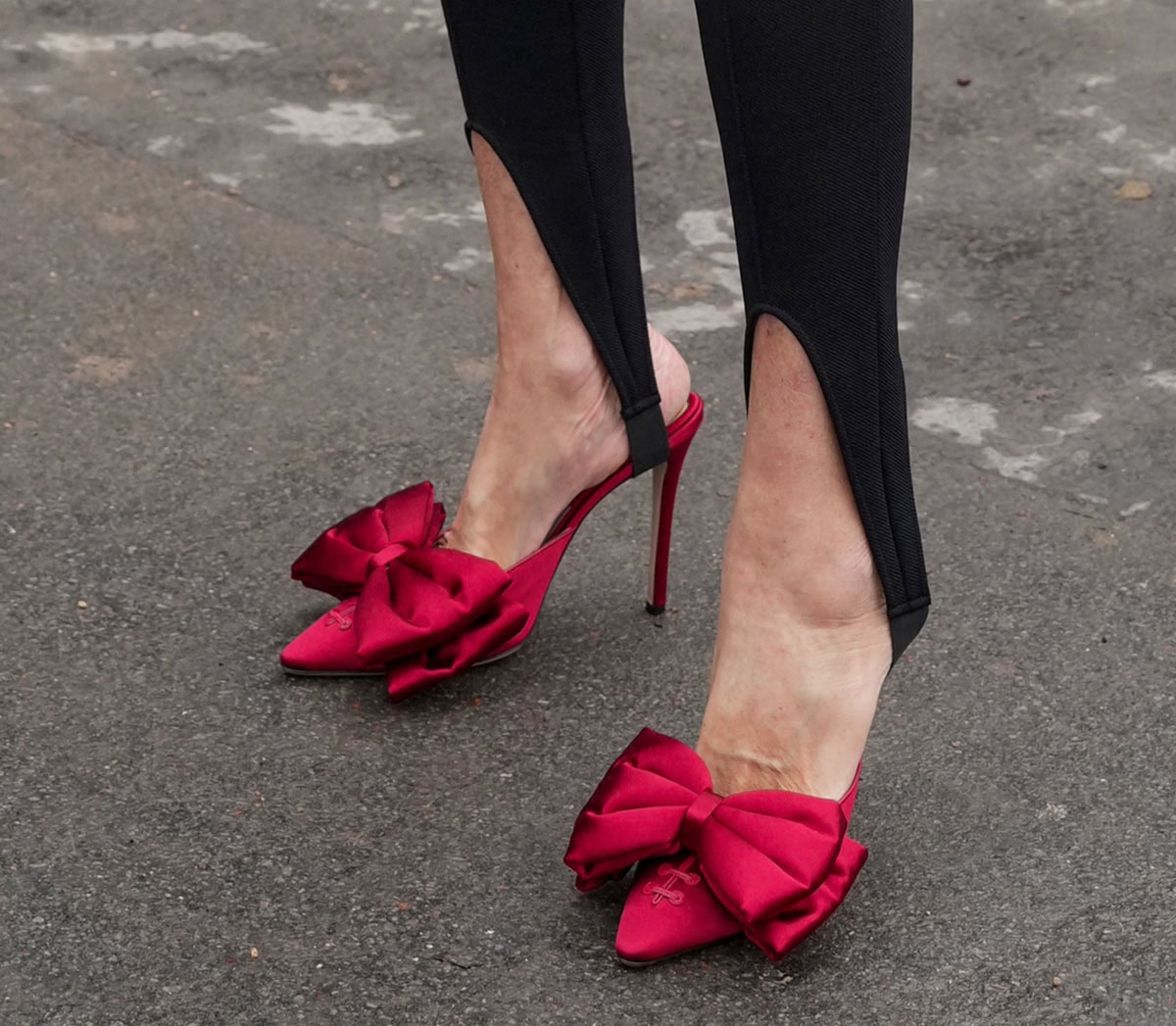 Elisabetta Dessy leans into bold femininity with red Valentino “Yolande” mules, defined by corset-inspired lacing and dramatically oversized double bows at the vamp