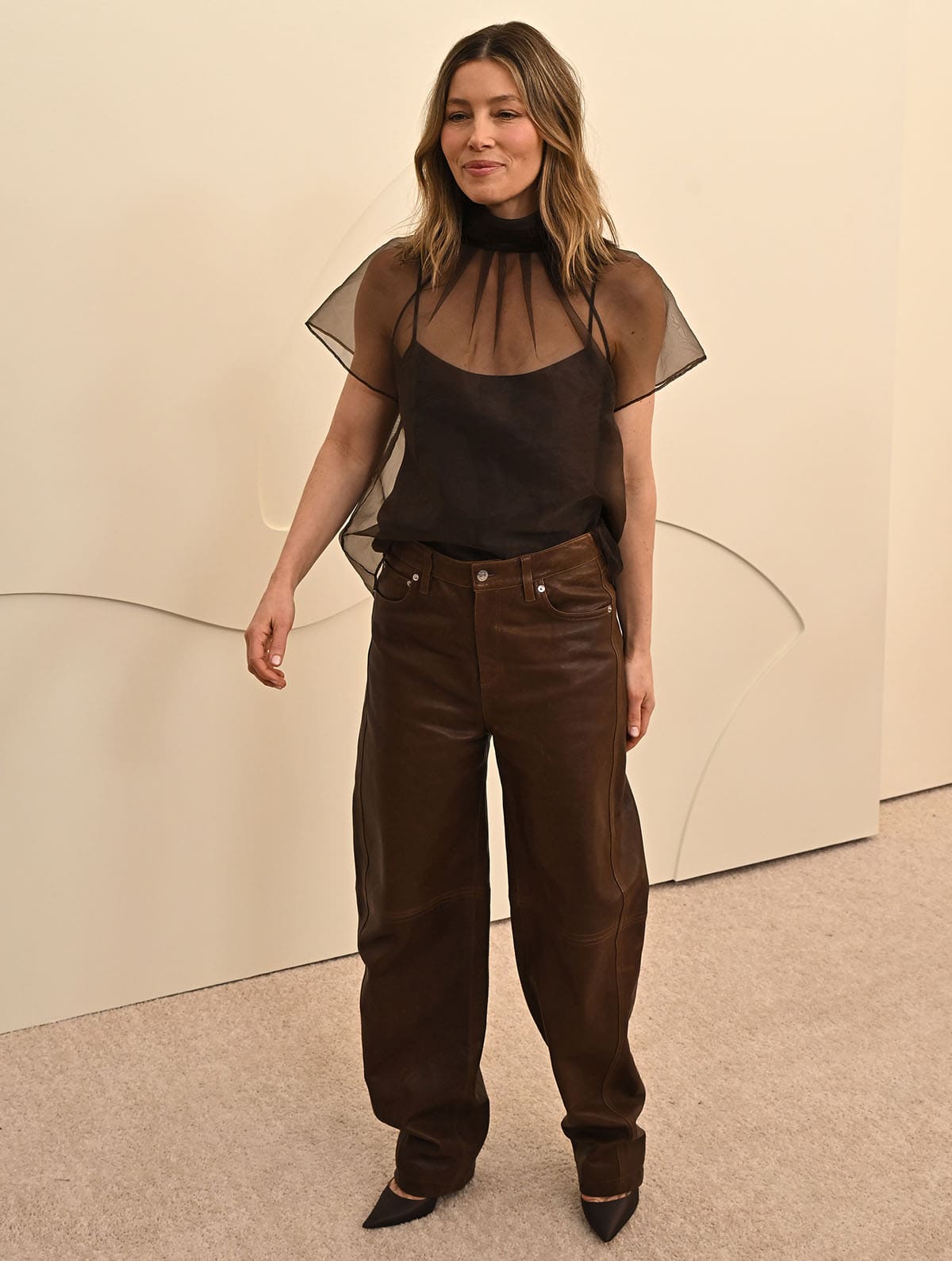 Jessica Biel completes her monochrome brown look with a sheer boxy blouse and leather curved pants by Simkhai