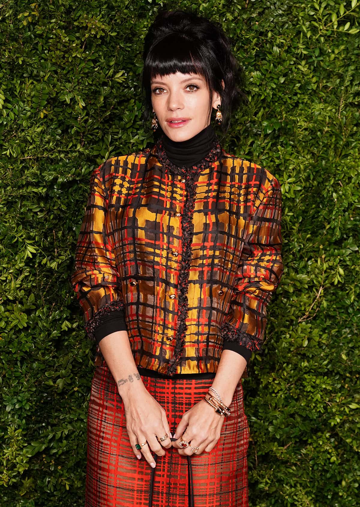 Lily Allen brings color to the black carpet in a Chanel Spring 2026 skirt suit, featuring a plaid jacket in yellow, orange, and black with frayed trims and a red woven plaid skirt