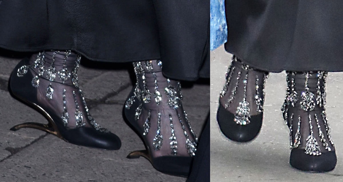 Melissa McCarthy wears a striking pair of Alexander McQueen boots in see-through mesh with leather panels, cascading crystals, and sculptural, horizontal metal heels