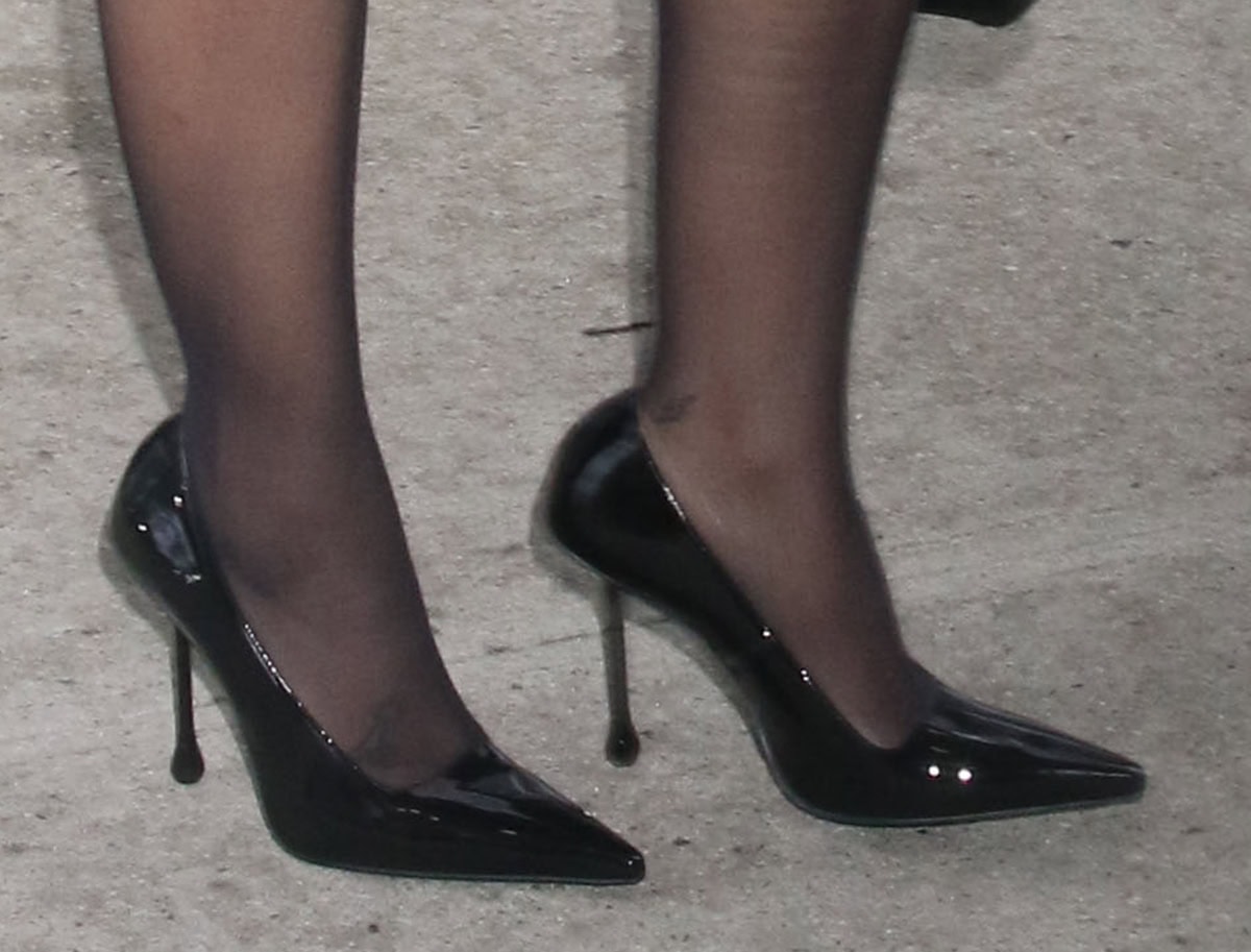 Alexandra Shipp wears the contemporary Jimmy Choo “Ixia” drop heel pumps in shiny black patent leather