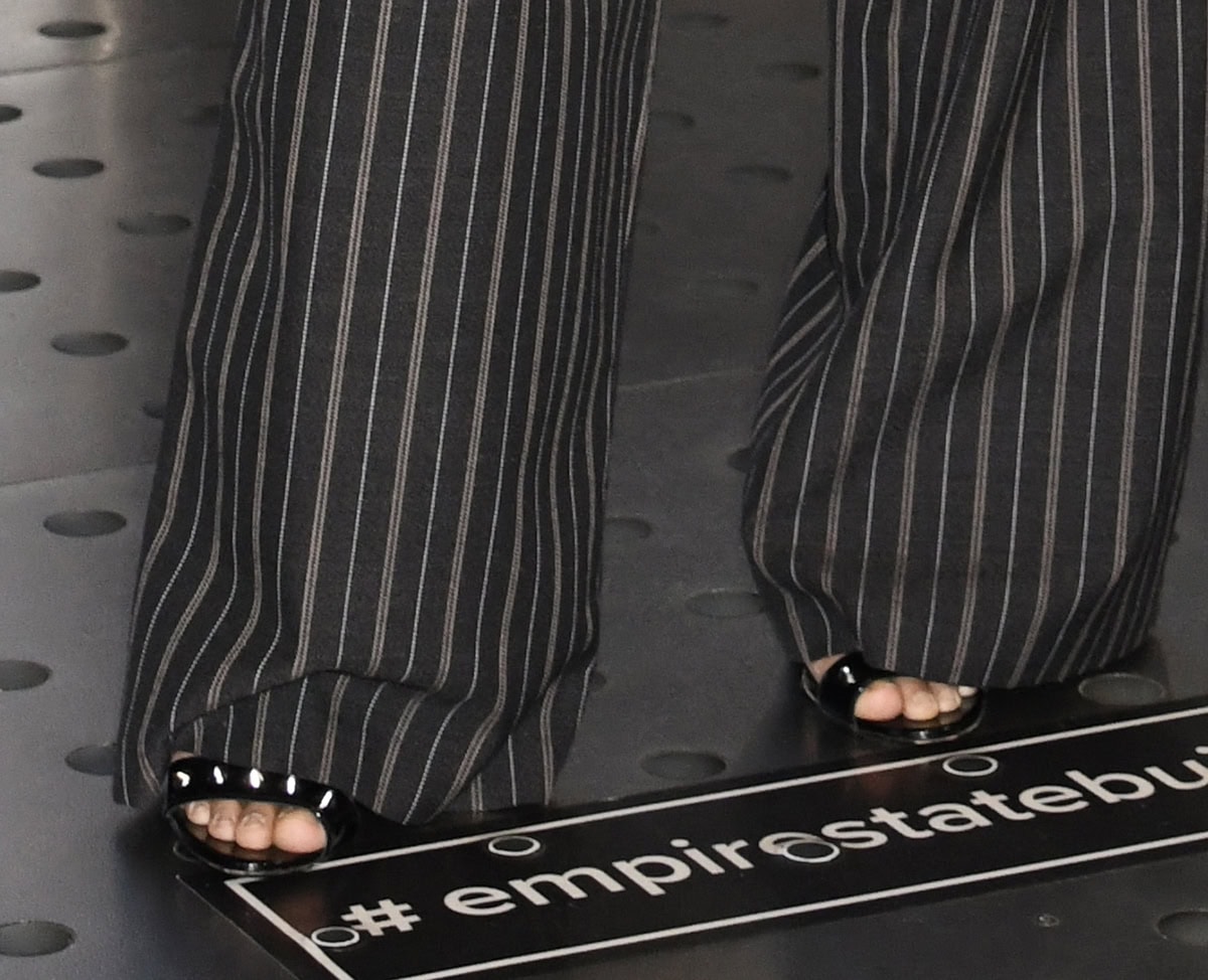 Avantika Vandanapu adds tough-chic edge to business dressing with the DSquared2 “Gothic” sandals in shiny black patent leather with silver-tone spike studs