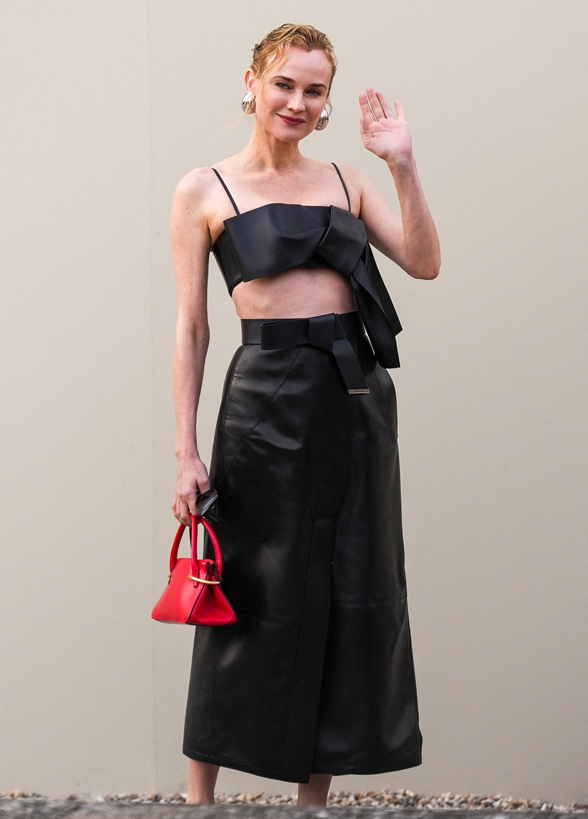 Diane Kruger embraces Givenchy's bow element by pairing her bow pumps with a black bow cropped top and a leather midi skirt with a bow waist