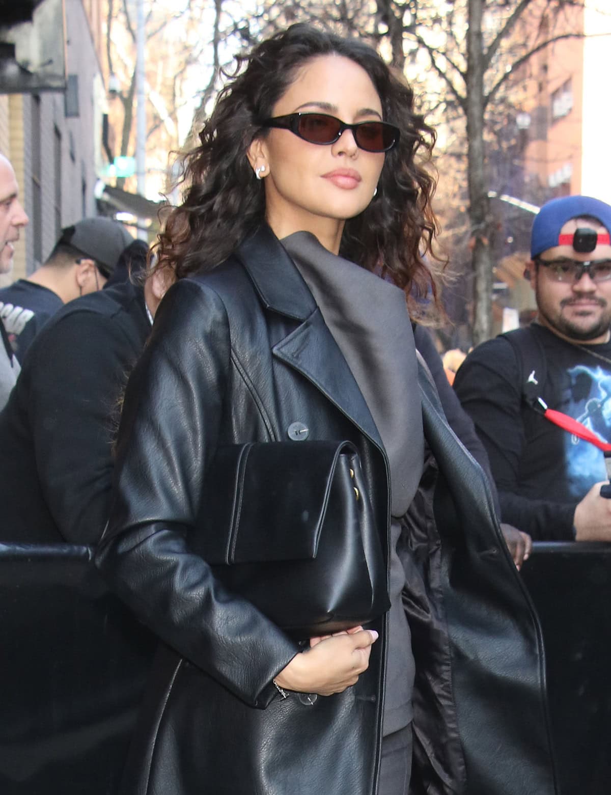 Eiza Gonzalez styles her hair in curls and accessorizes with sleek sunnies and a black Manu Atelier bag