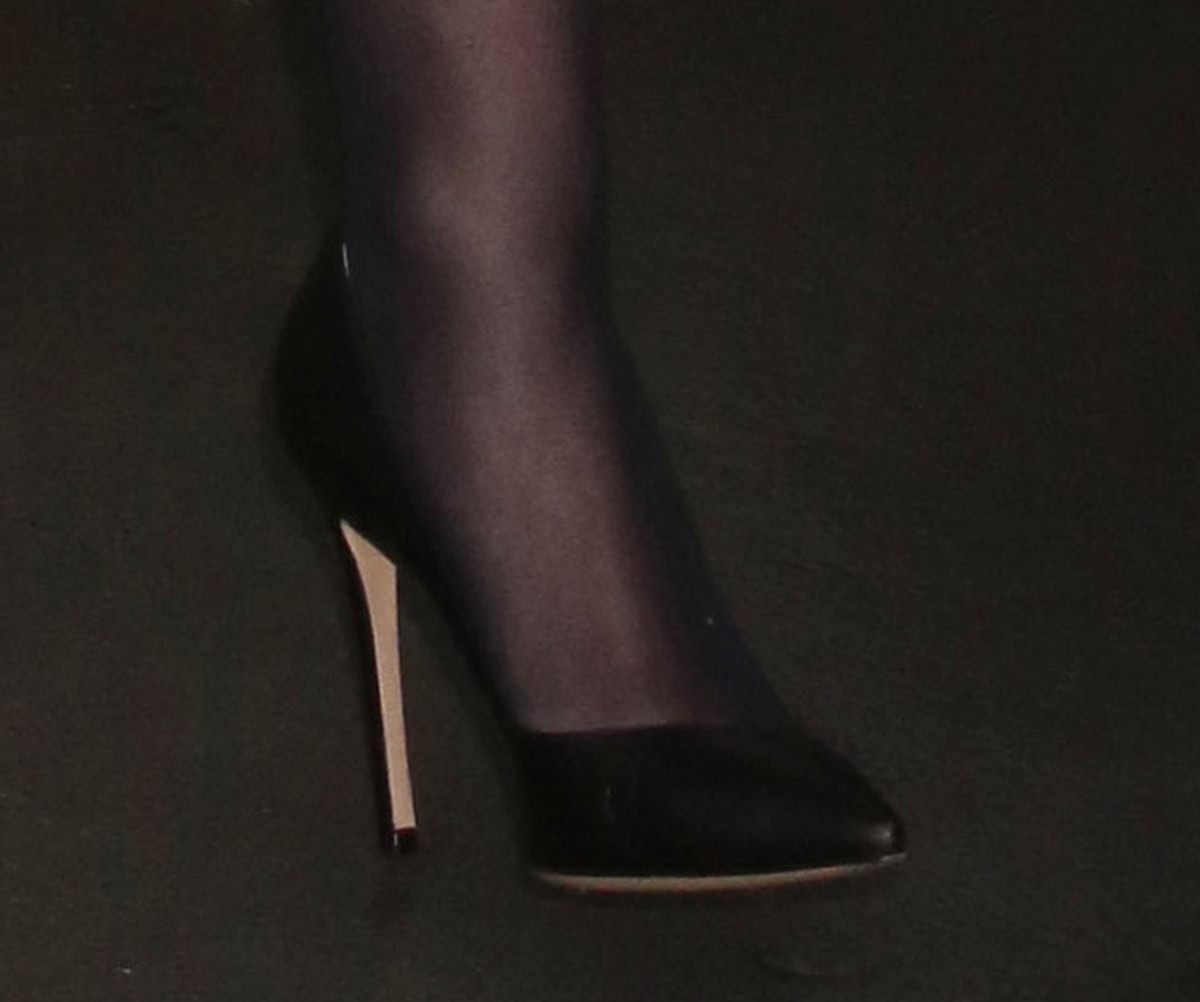 Lili Reinhart opts for timeless black leather Jimmy Choo “Romy” pumps, featuring sharp pointed toes and slim stiletto heels that elongate her legs beneath sheer black tights