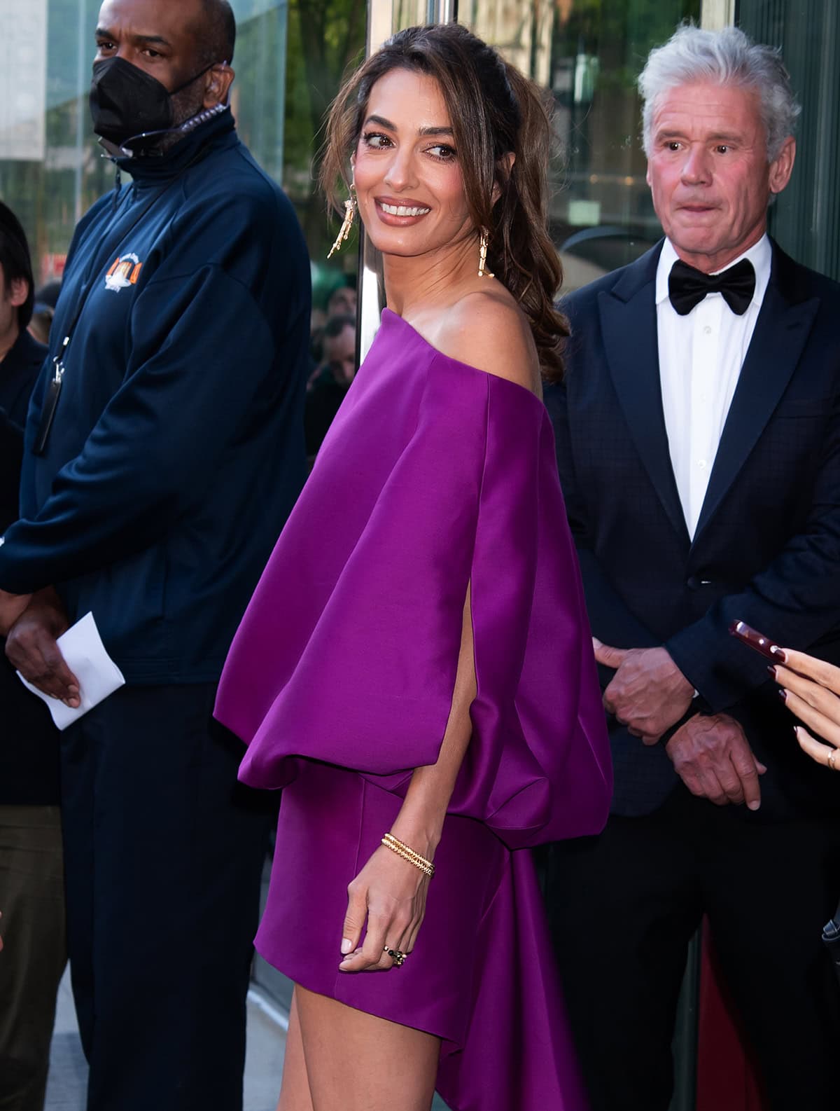 Amal Clooney elevates her sculptural Balenciaga mini with Panthère de Cartier drop earrings and stacked gold bracelets, adding fluid movement and a refined metallic finish to the look