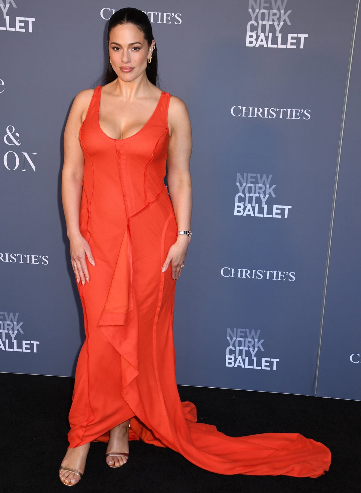 Ashley Graham was red hot in her dramatic gown with a low-cut scoop neckline, uneven, irregular seams, and a dramatic train