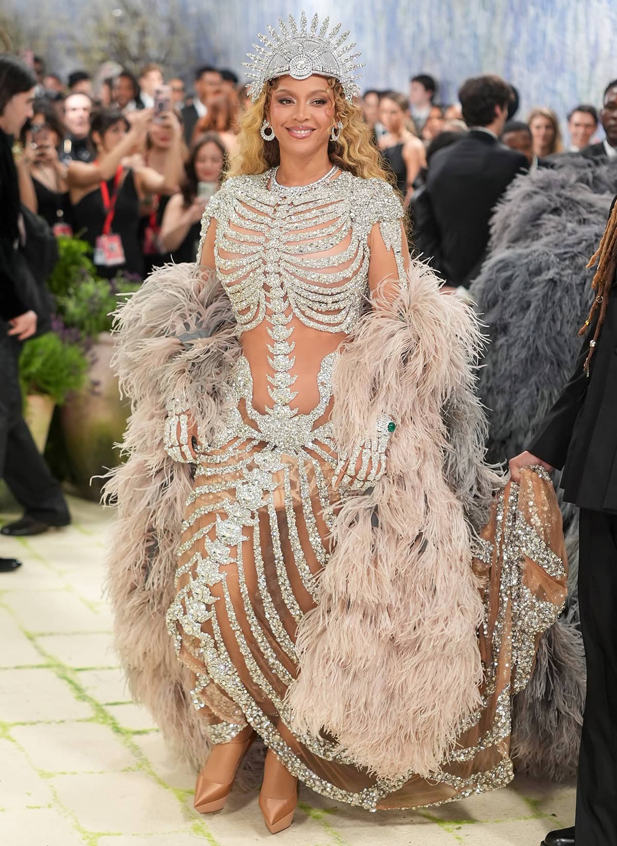 Beyonce teams her platform pumps with a daring skeleton-inspired gown adorned with gems and crystals, finished with a feather cape