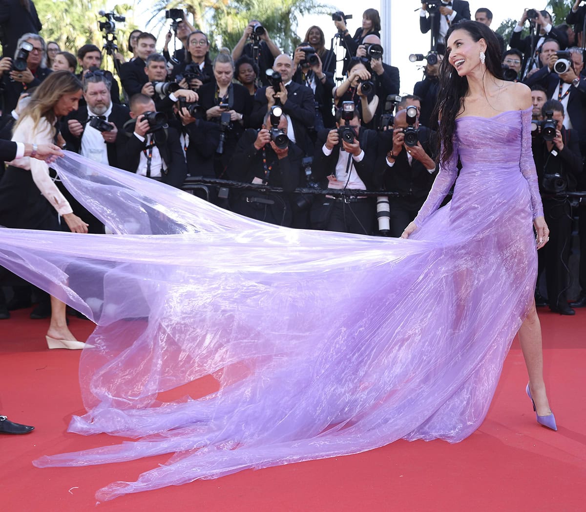 Demi Moore opts for head-to-toe purple, pairing her purple pumps with a custom purple Gucci gown made of shiny layers of sheer fabric with an off-the-shoulder neckline, long sleeves, and an airy skirt