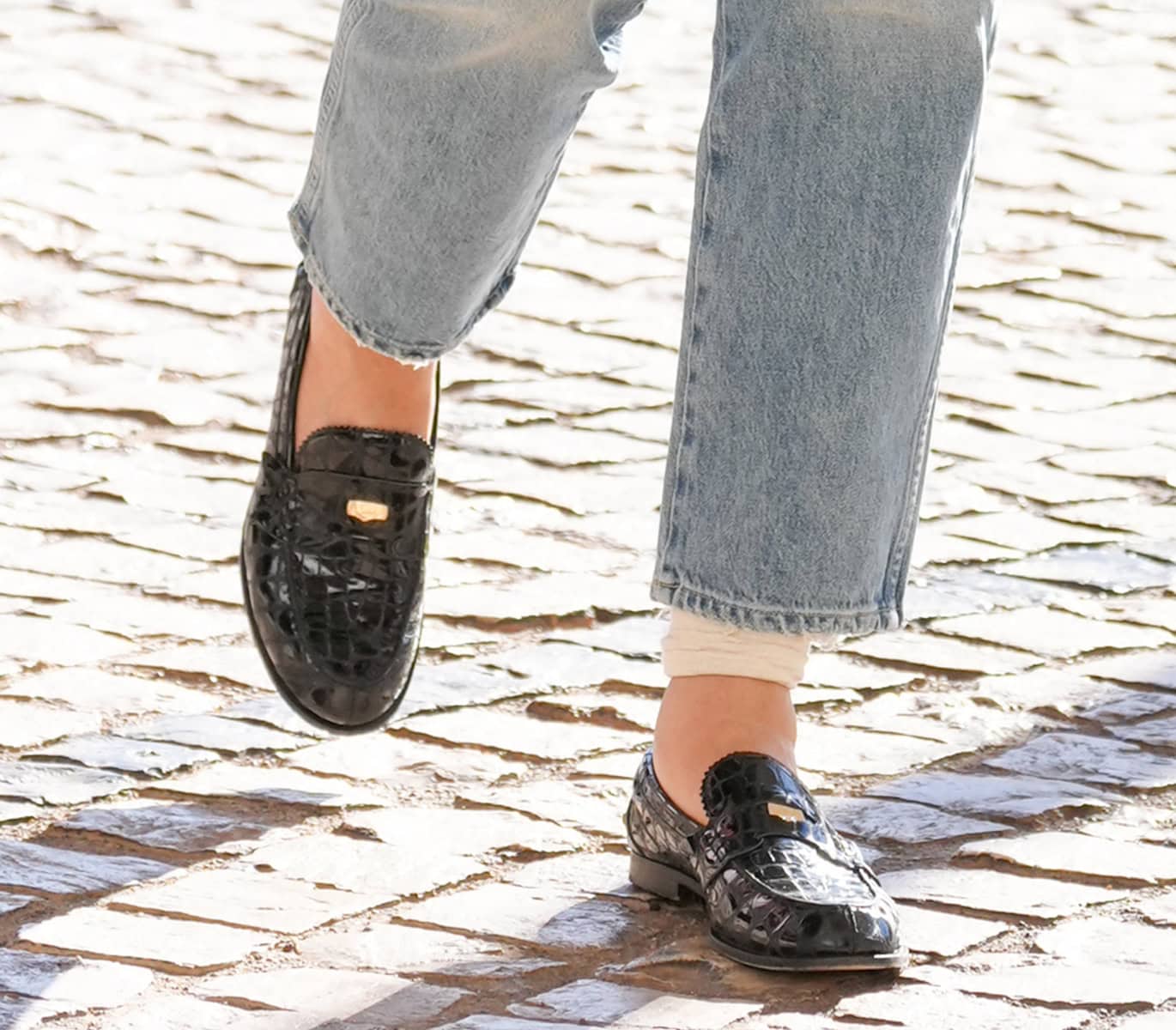 Heidi Klum slips into a pair of shiny black croc loafers with pinked trims and a penny strap with a gold-tone logo accent