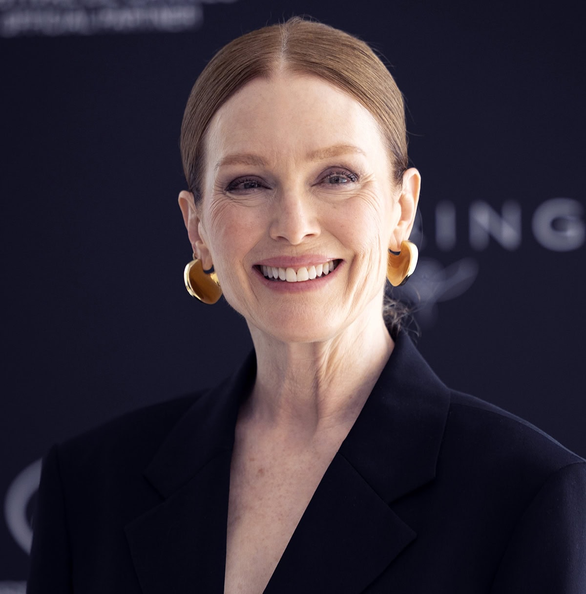 Julianne Moore wears minimal makeup, styles her hair in a low bun, and accessorizes with statement gold earrings