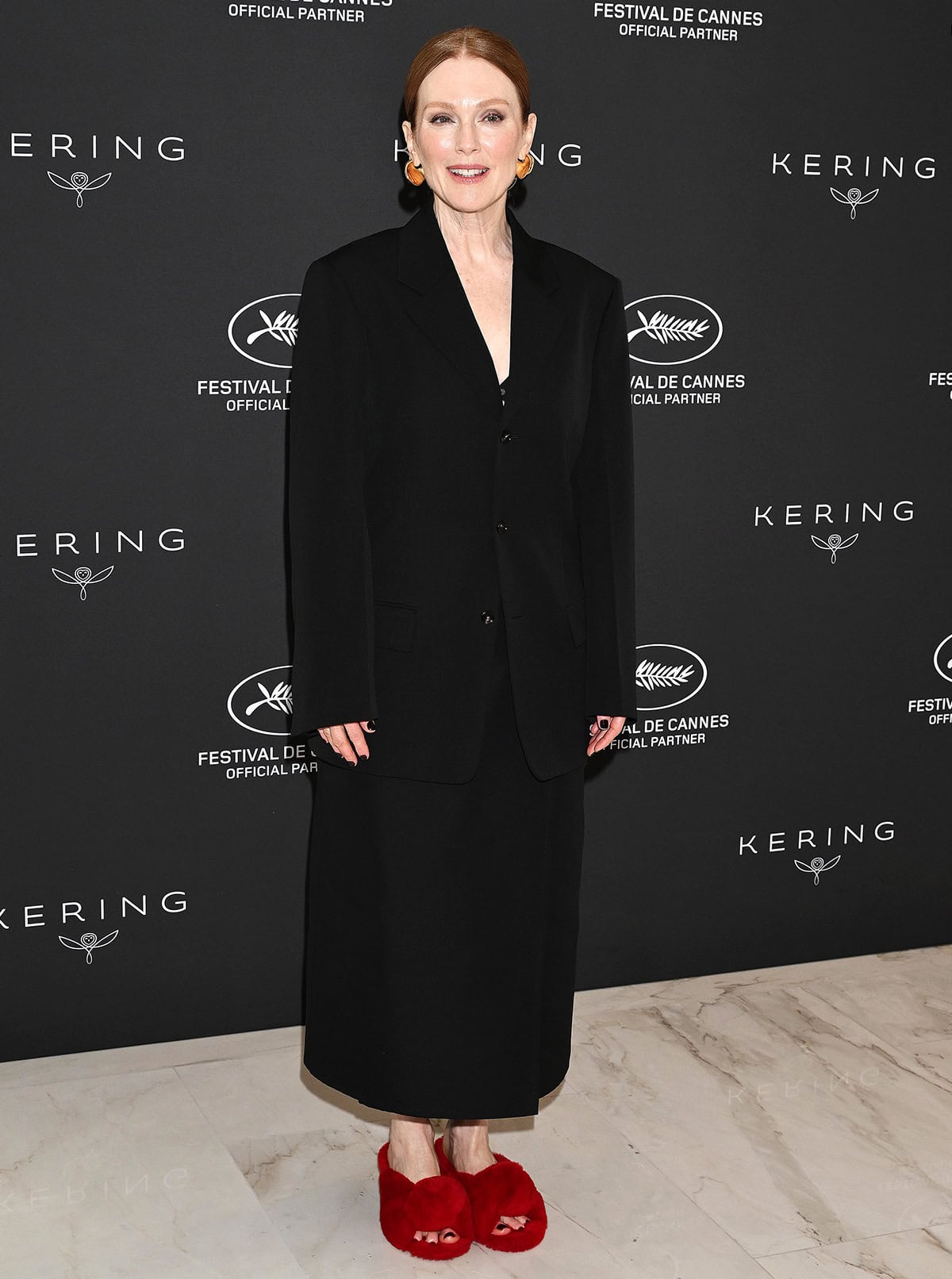Julianne Moore pairs her vibrant red mules with an oversized black jacket and an ankle-length column skirt