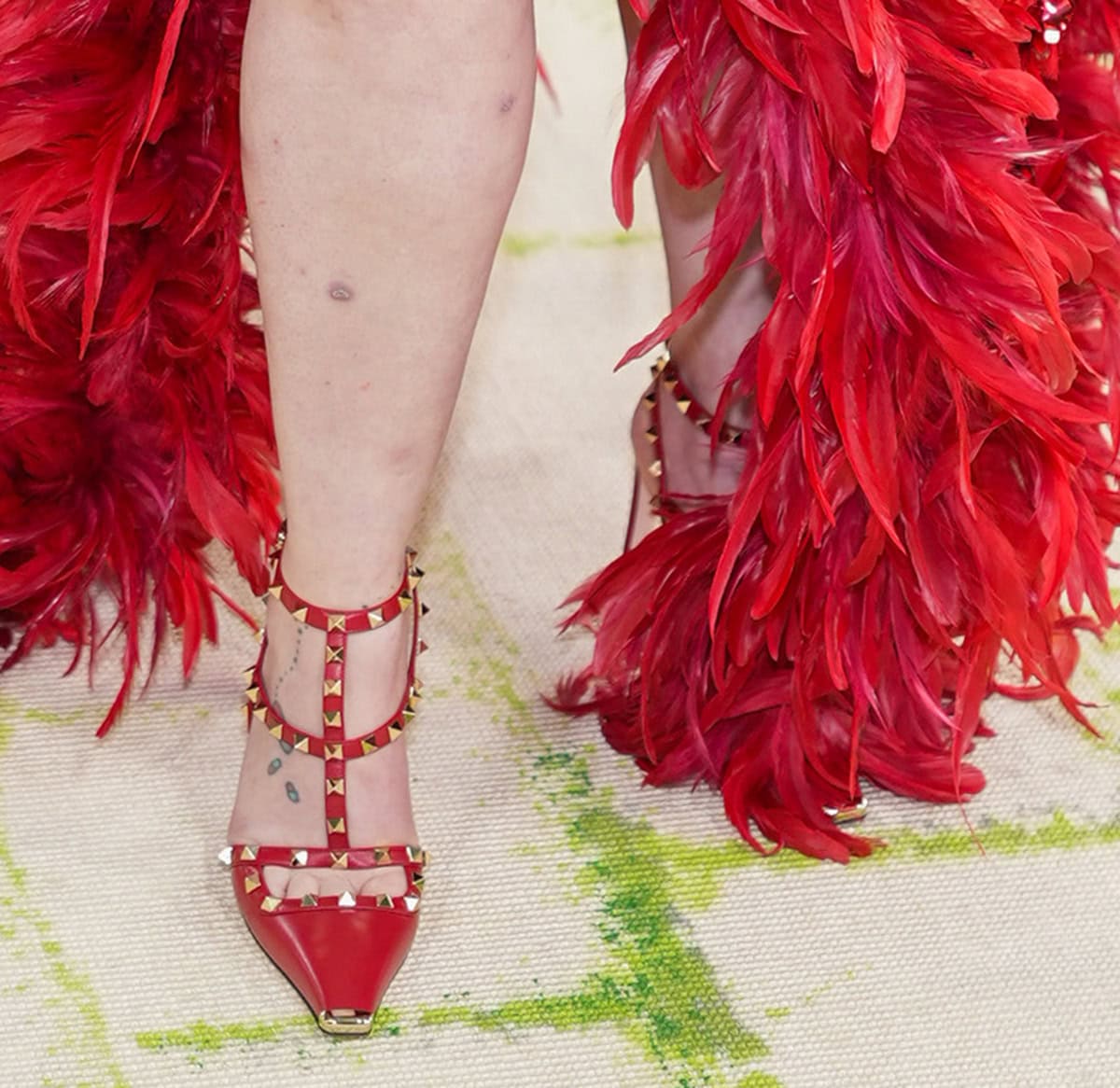 Lena Dunham chooses an all-red look, slipping her feet into the Valentino Rockstud pumps with a squared platinum-finish metal toe cap, a rectangular cutout across the toes, and studded straps