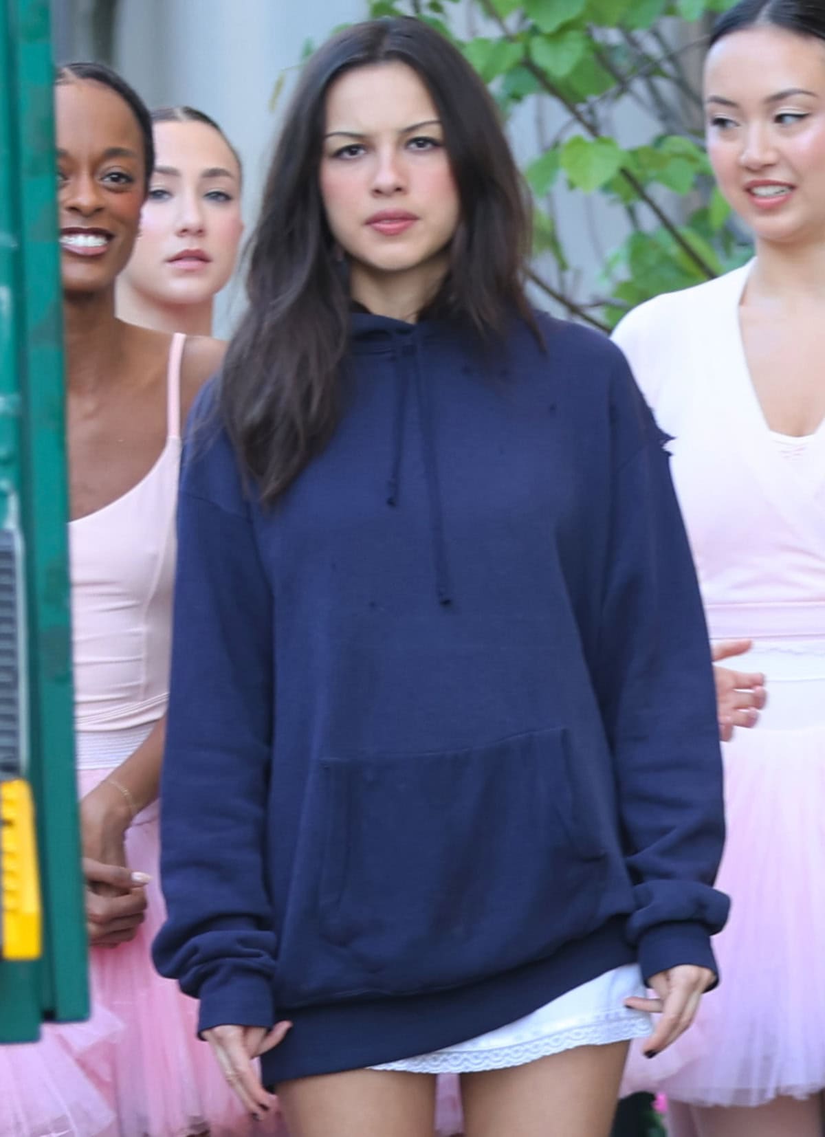Olivia Rodrigo keeps her beauty look understated with softly defined eyes, rosy cheeks, a muted pink lip, and loose dark layers framing her face as she stands among ballerinas in Uptown Manhattan