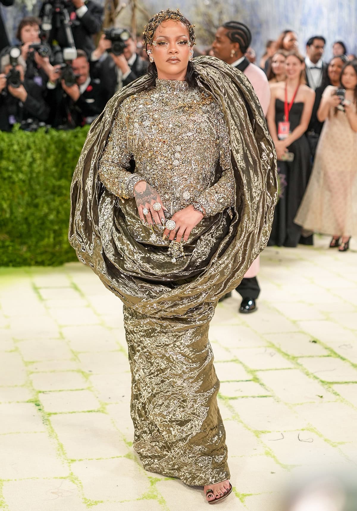 Rihanna pairs her toe-ring sandals with a Maison Margiela Couture gown featuring a fully embellished turtleneck bodice, long sleeves, and a sculptural piece made from fine copper oscillating duchess woven with recycled computer wire