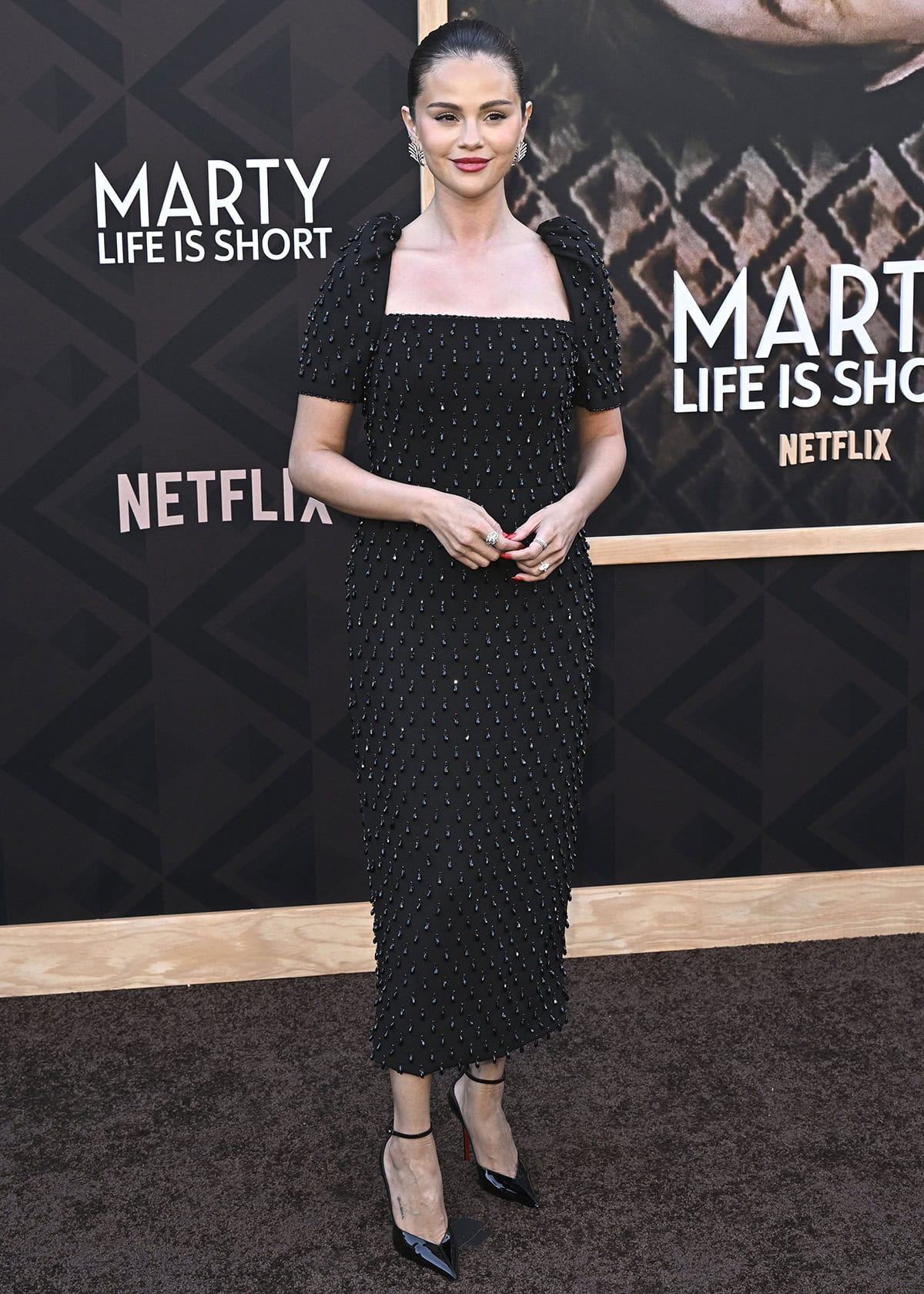Selena Gomez shines in her black Carolina Herrera dress featuring a square neckline, puff shoulders, and crystal drop beadwork