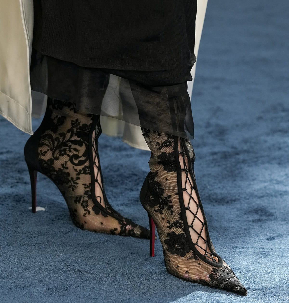 Shailene Woodley adds edge to her simple look with Christian Louboutin “KM” knee-high boots made of embroidered floral lace with leather lace-up ties down the center and slim stiletto heels